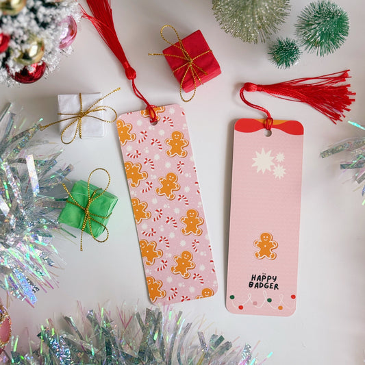 Two Christmas-themed bookmarks with decorative tinsel and small gifts in the background.