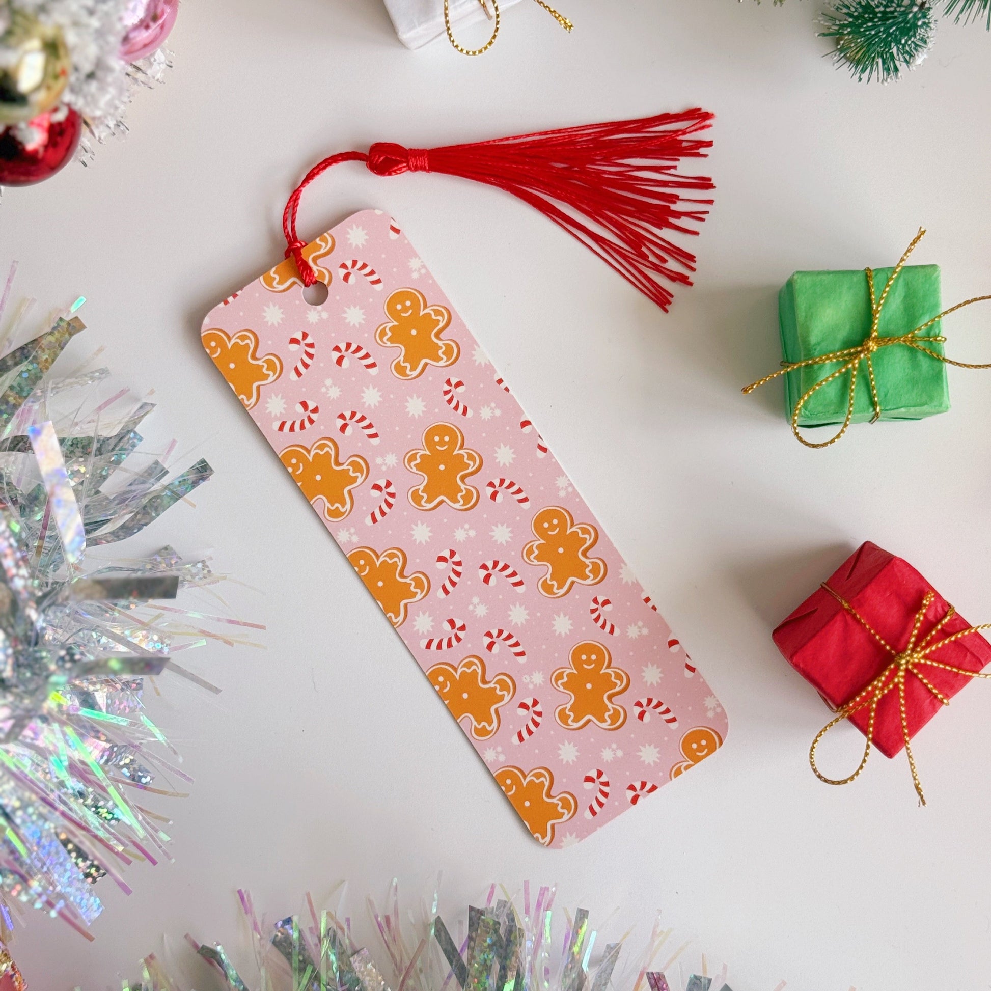 Decorative Christmas bookmark with gingerbread design on a festive background with tinsel and small gift boxes.
