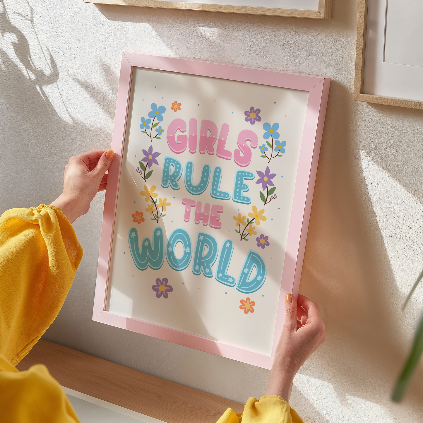 A hand lettered quote print, featuring the words 'girls rule the world' in pink and blue. Surrounded by colourful floral illustrations. 