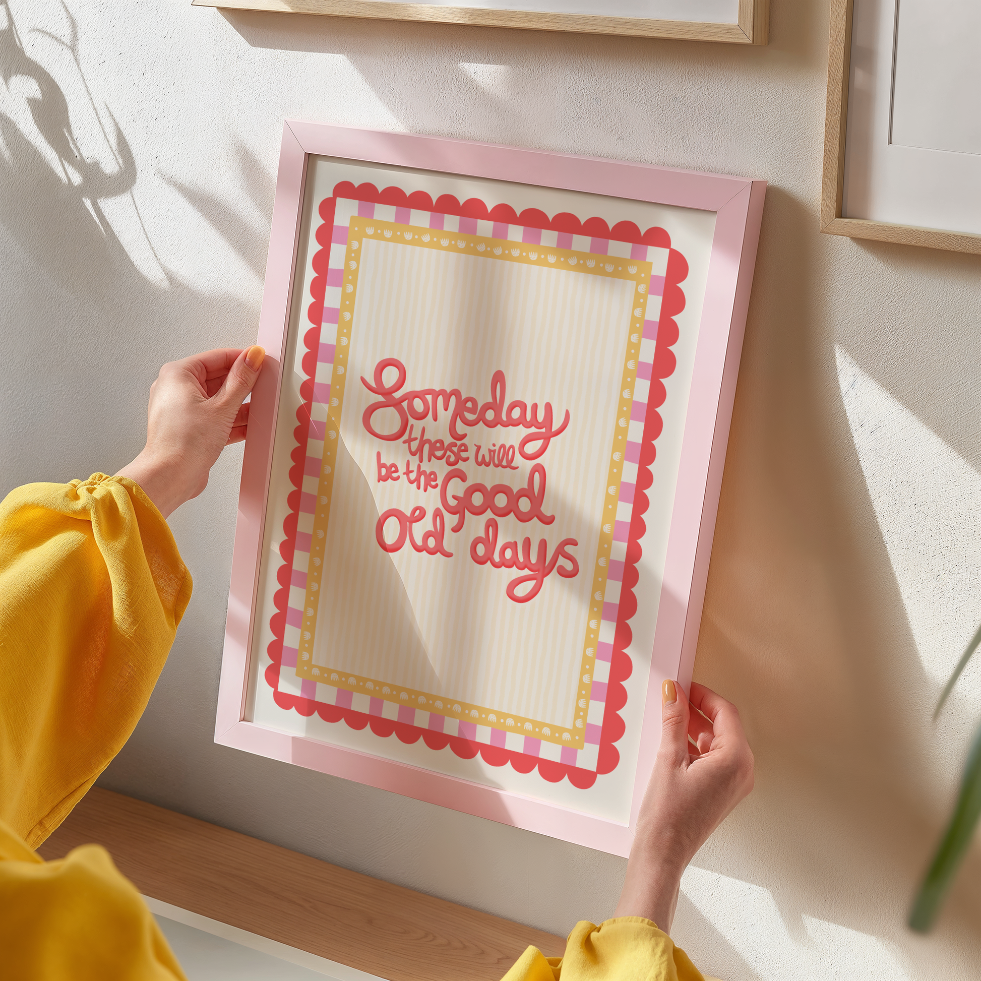 Person holding a framed print with 'Someday these will be the good old days' text.