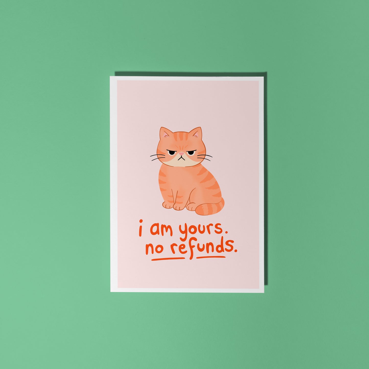 An illustrated card with a drawing of a grumpy orange cat, and words underneath that read 'I am yours, no refunds.'