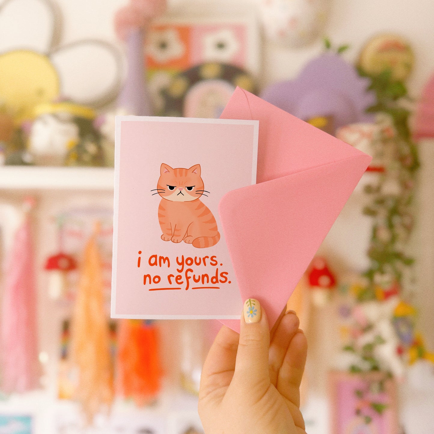 An illustrated card with a drawing of a grumpy orange cat, and words underneath that read 'I am yours, no refunds.'