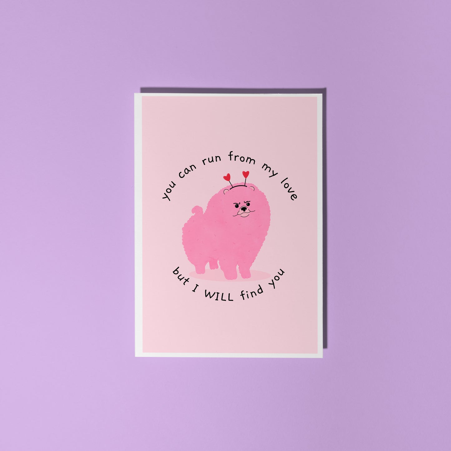 A pink love themed card with an illustration of a pink grumpy dog on the front and text that reads 'you can run from my love, but I WILL find you'.