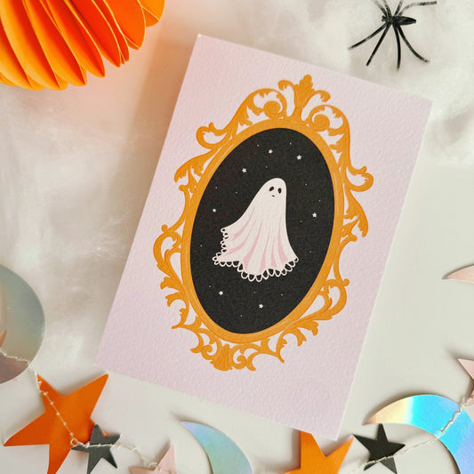 A halloween themed postcard of a ghost in a golden ornate frame.