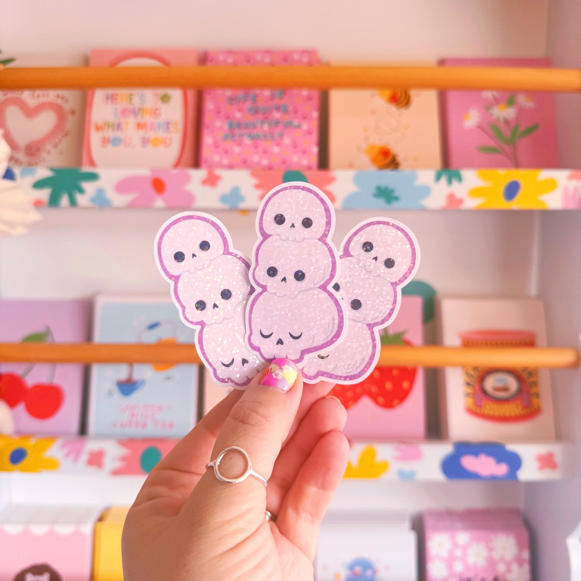 A holographic sticker featuring an illustration of three skulls stacked on top of one another.