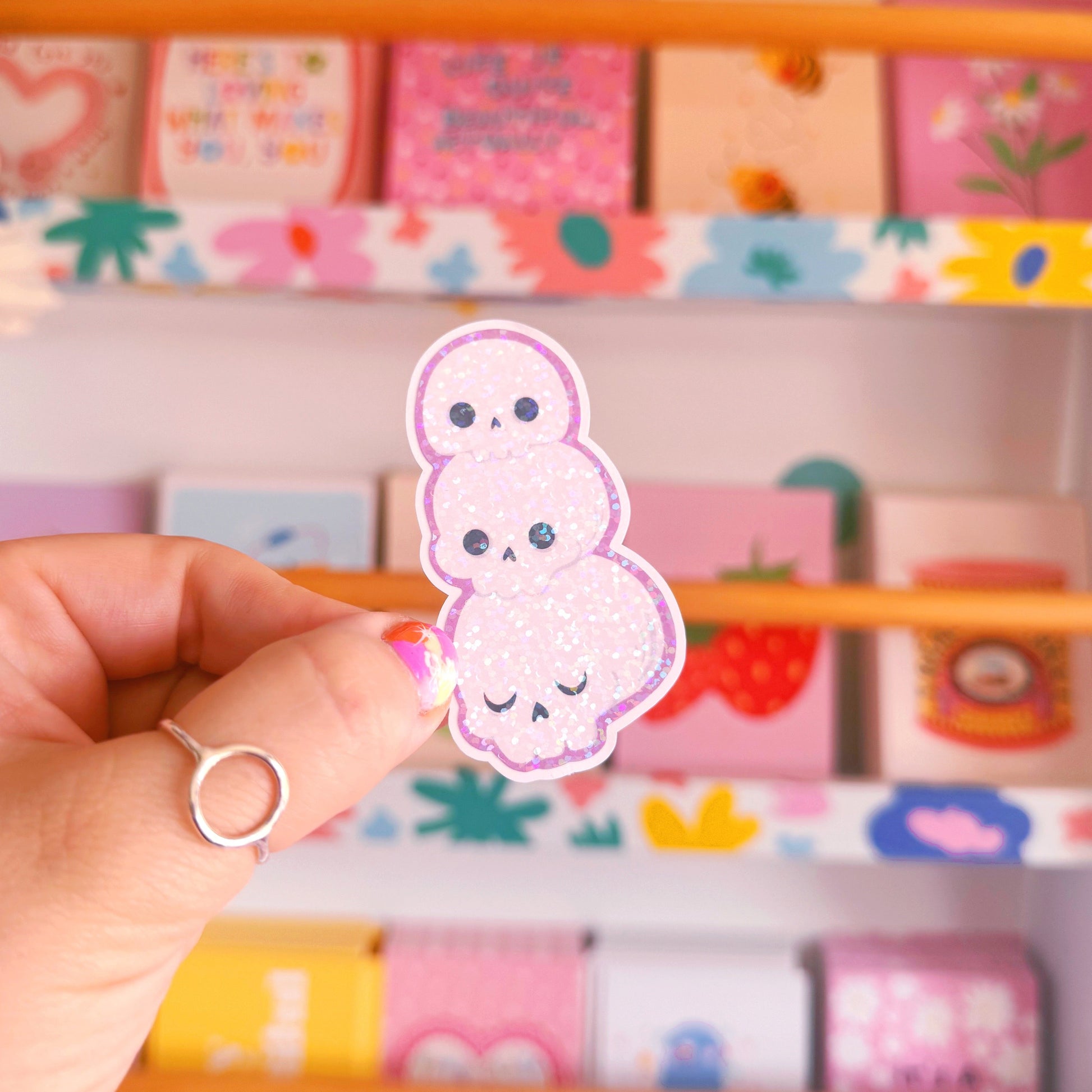 A holographic sticker featuring an illustration of three skulls stacked on top of one another.