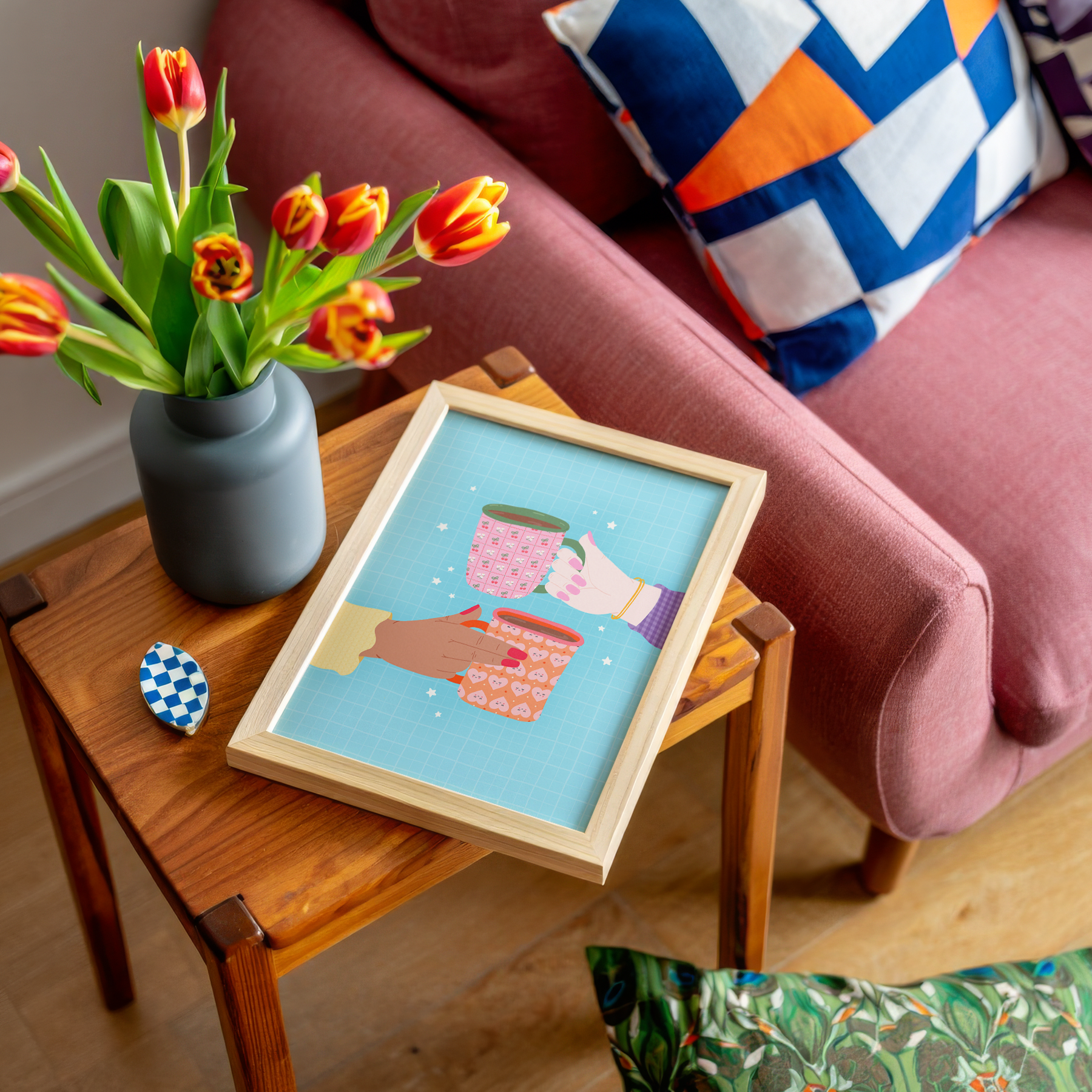 An illustrated print of two hands holding a colourful patterned mug each. The print has a blue background with little star illustrations.