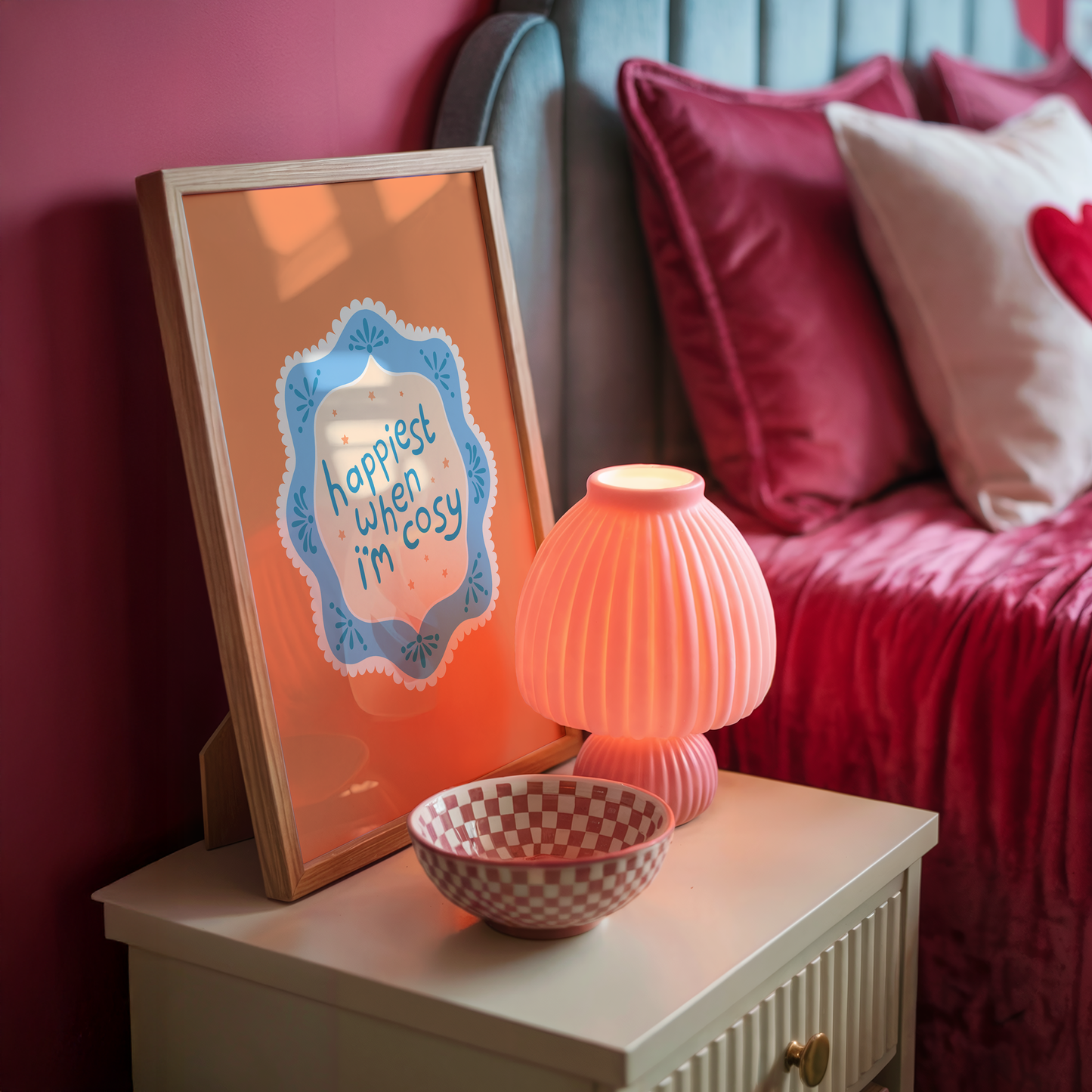 An orange print with a quote inside an illustrated blue decorative border - which says 'happiest when I'm cosy'.