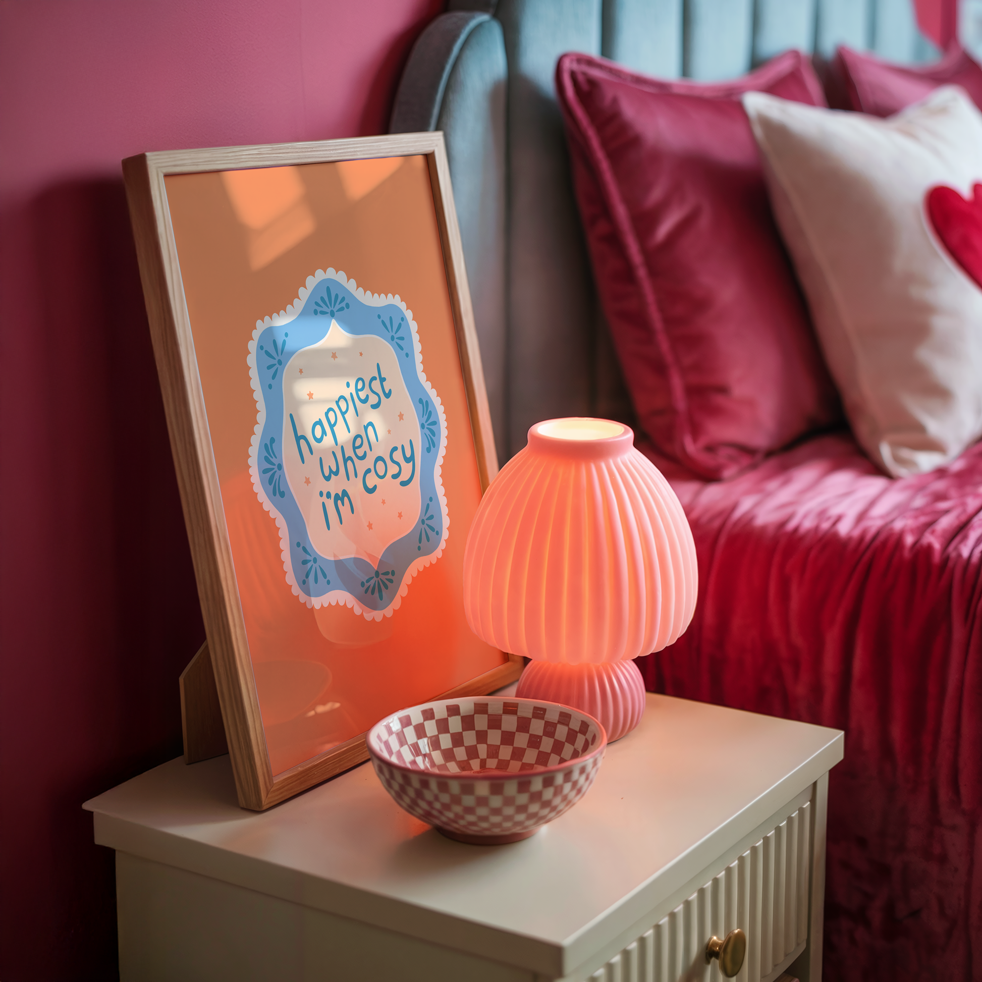 An orange print with a quote inside an illustrated blue decorative border - which says 'happiest when I'm cosy'.