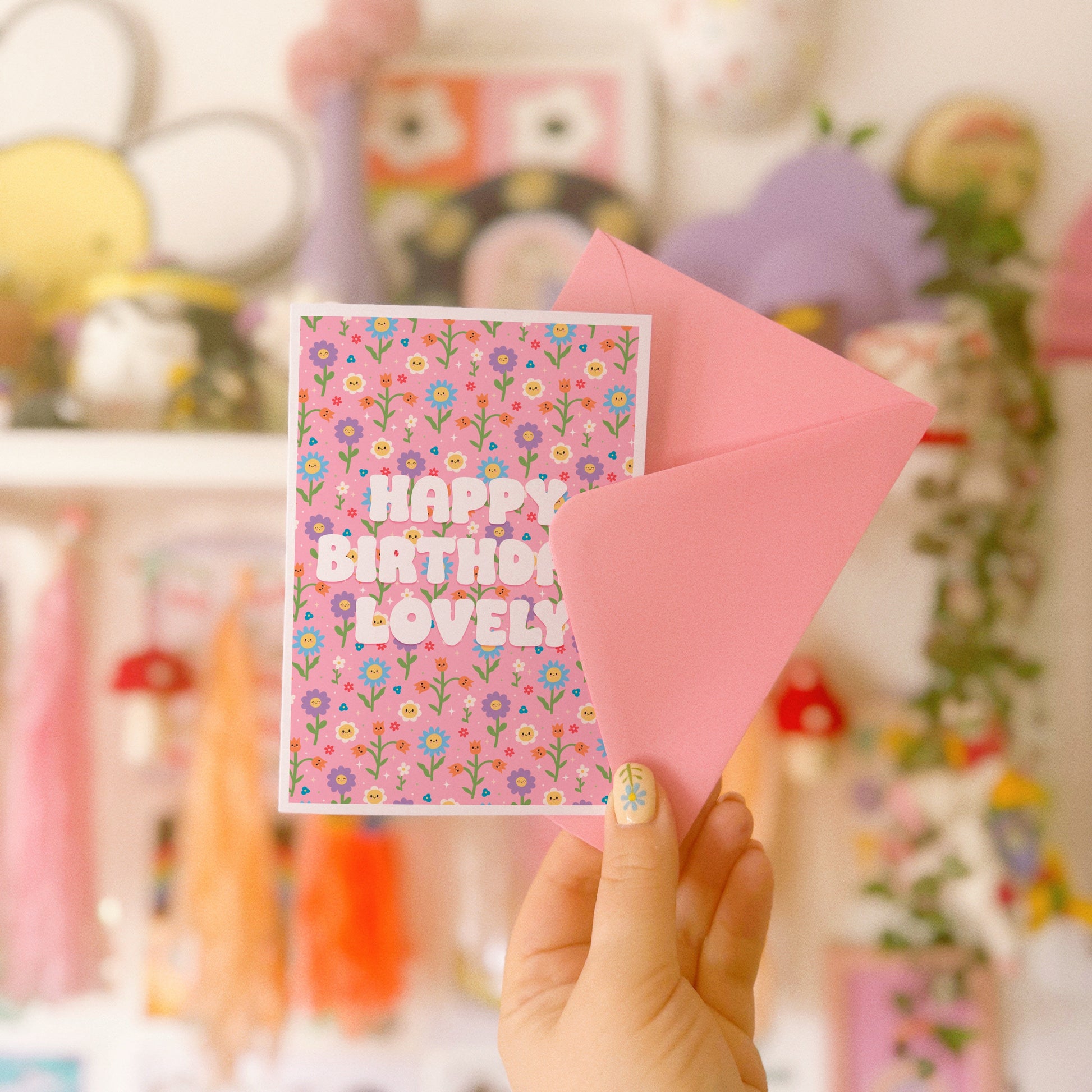 A pink floral birthday card, with white text that reads 'Happy Birthday Lovely'.