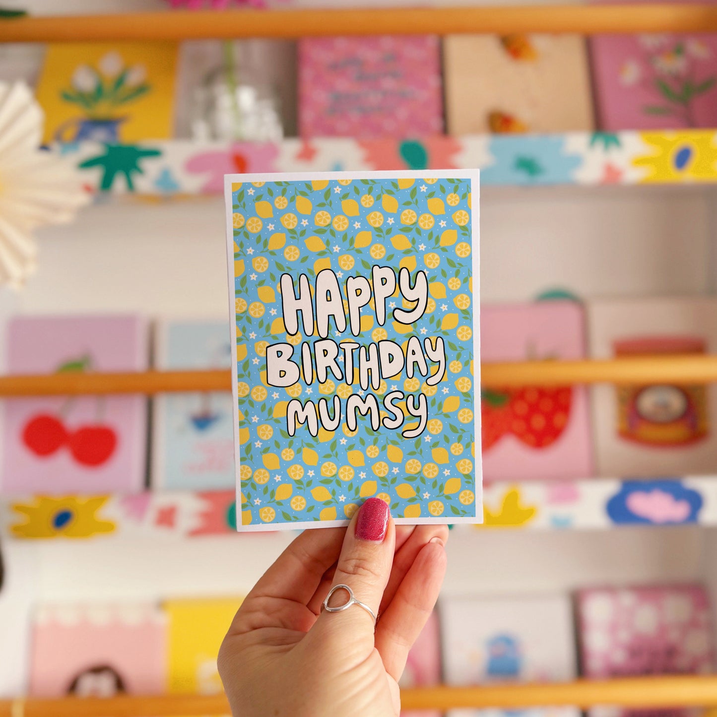 A blue card with a lemon pattern, and white chunky text that reads 'Happy Birthday Mumsy' in the centre.