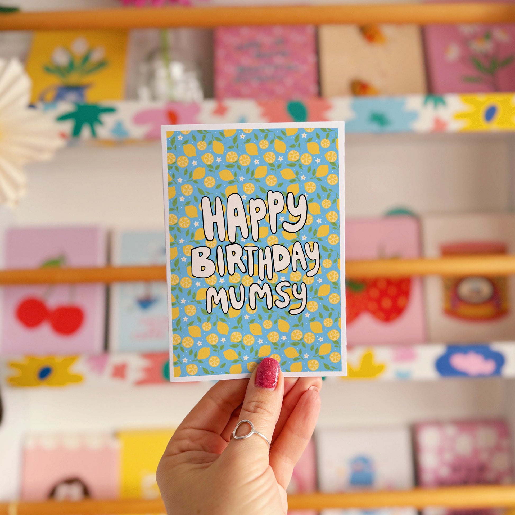 A blue card with a lemon pattern, and white chunky text that reads 'Happy Birthday Mumsy' in the centre.