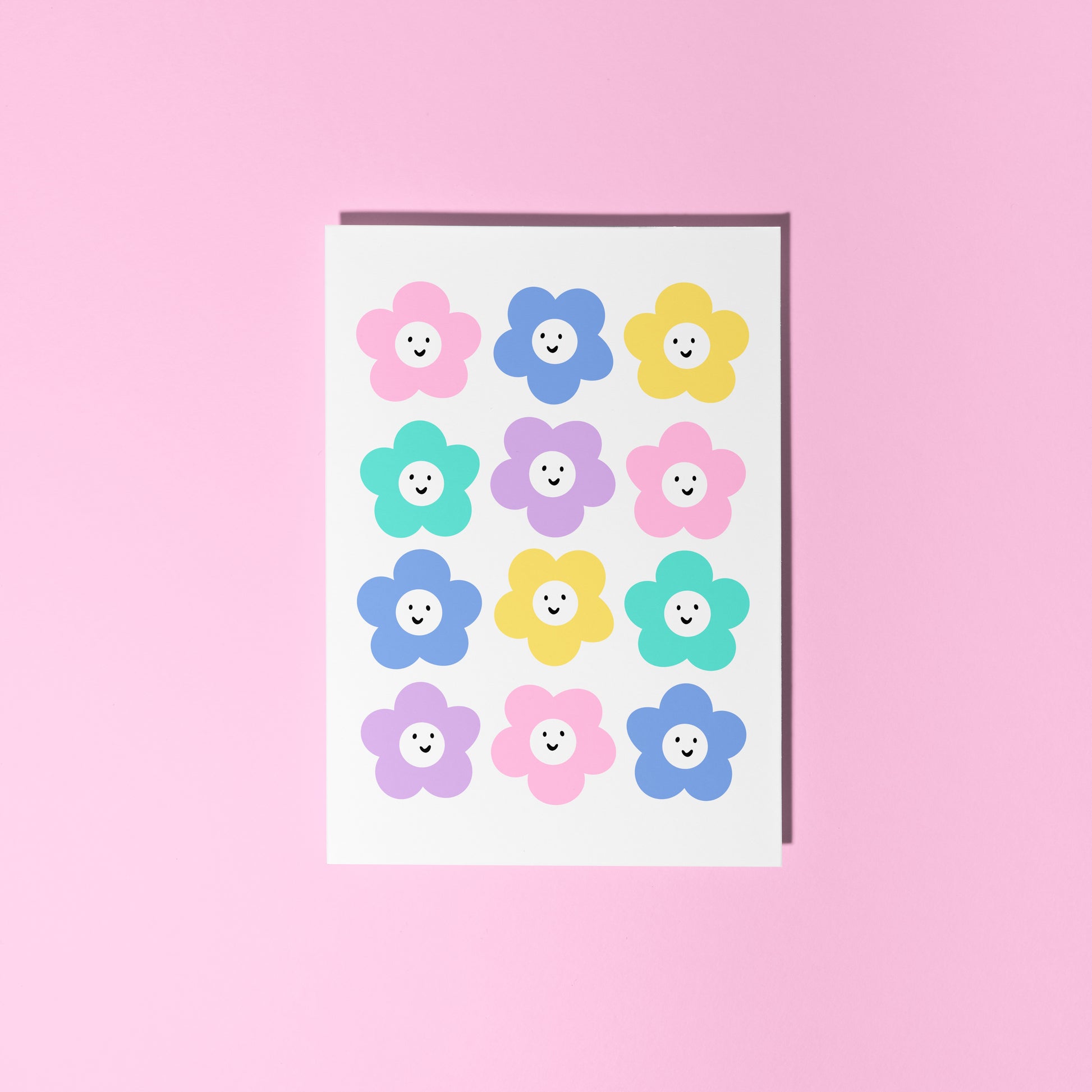 A white card with 12 colourful smiling daisy-like flowers on the front.
