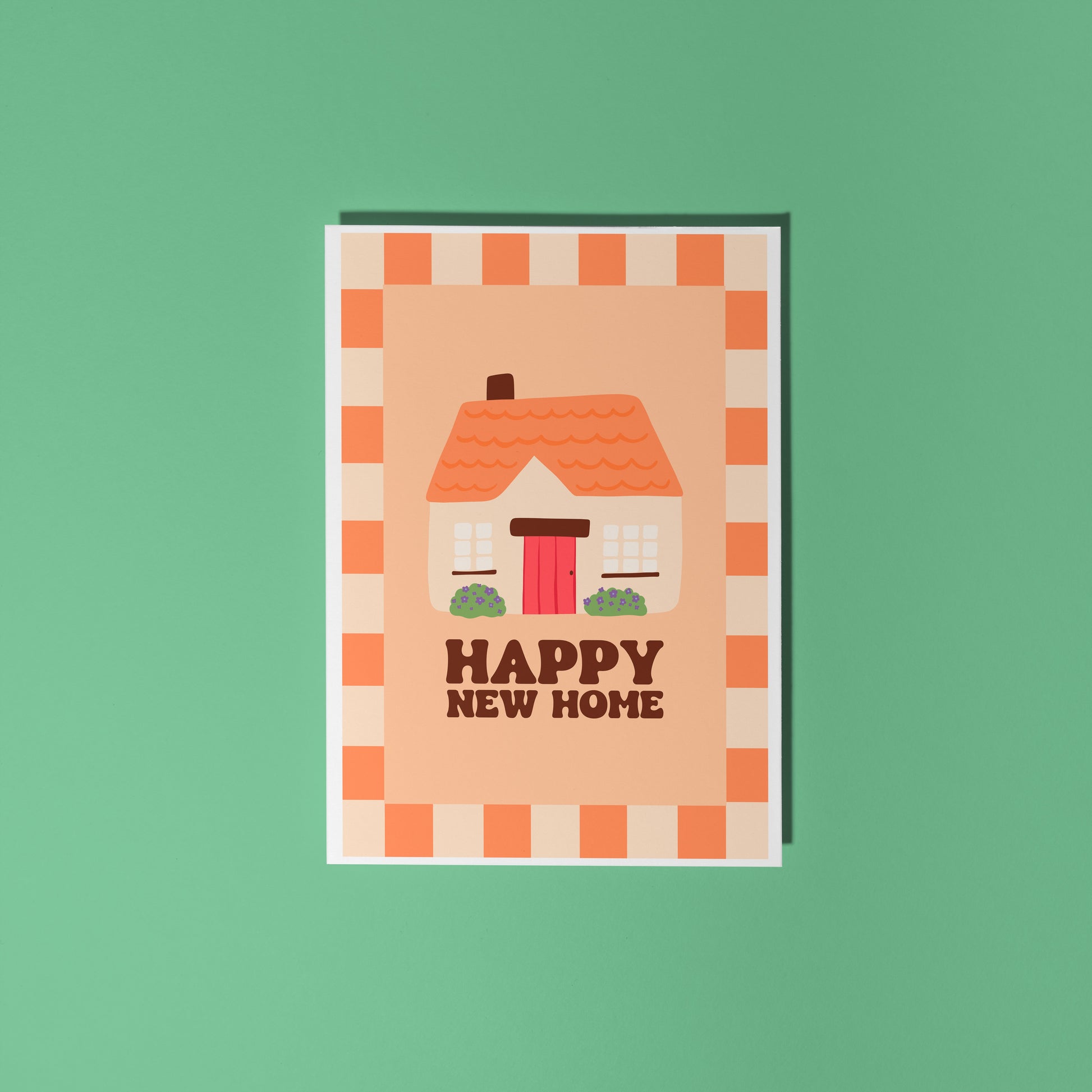 An orange card, with an illustration of a cute cottage on the front and the words 'happy new home' underneath.