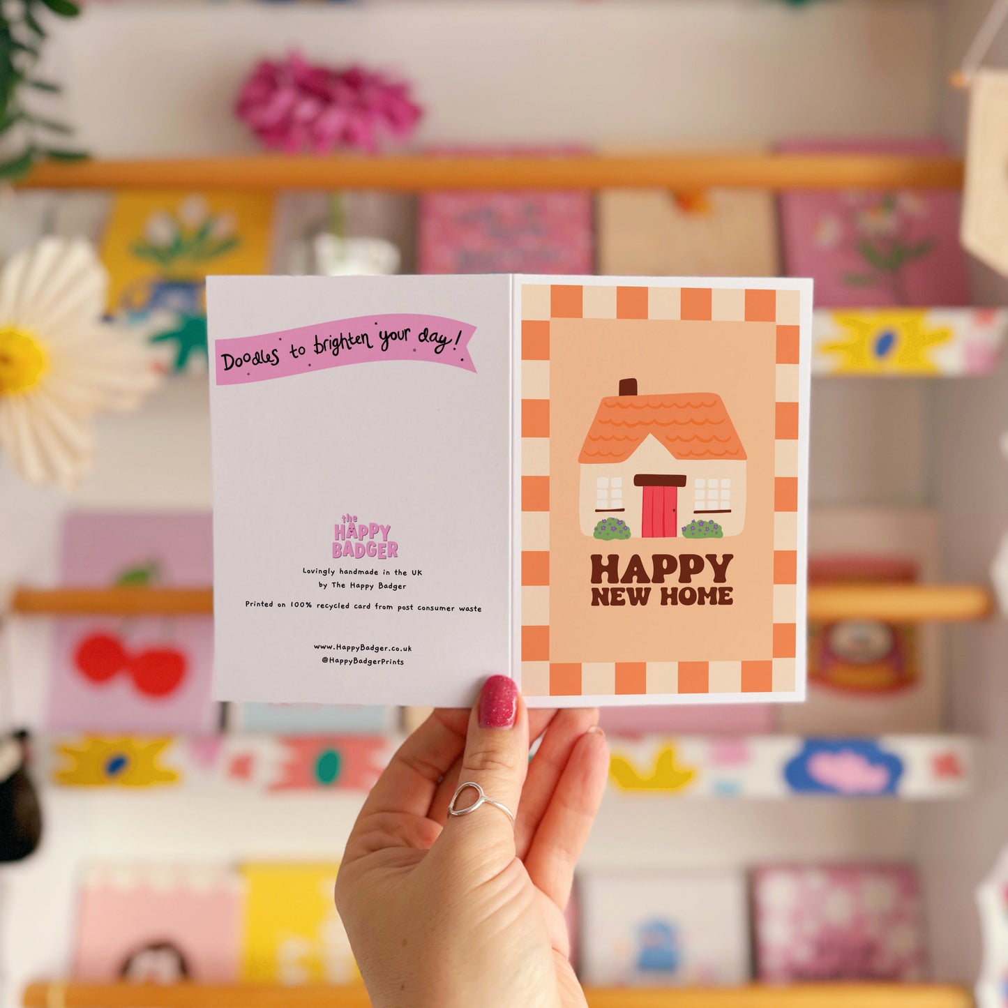 An orange card, with an illustration of a cute cottage on the front and the words 'happy new home' underneath.