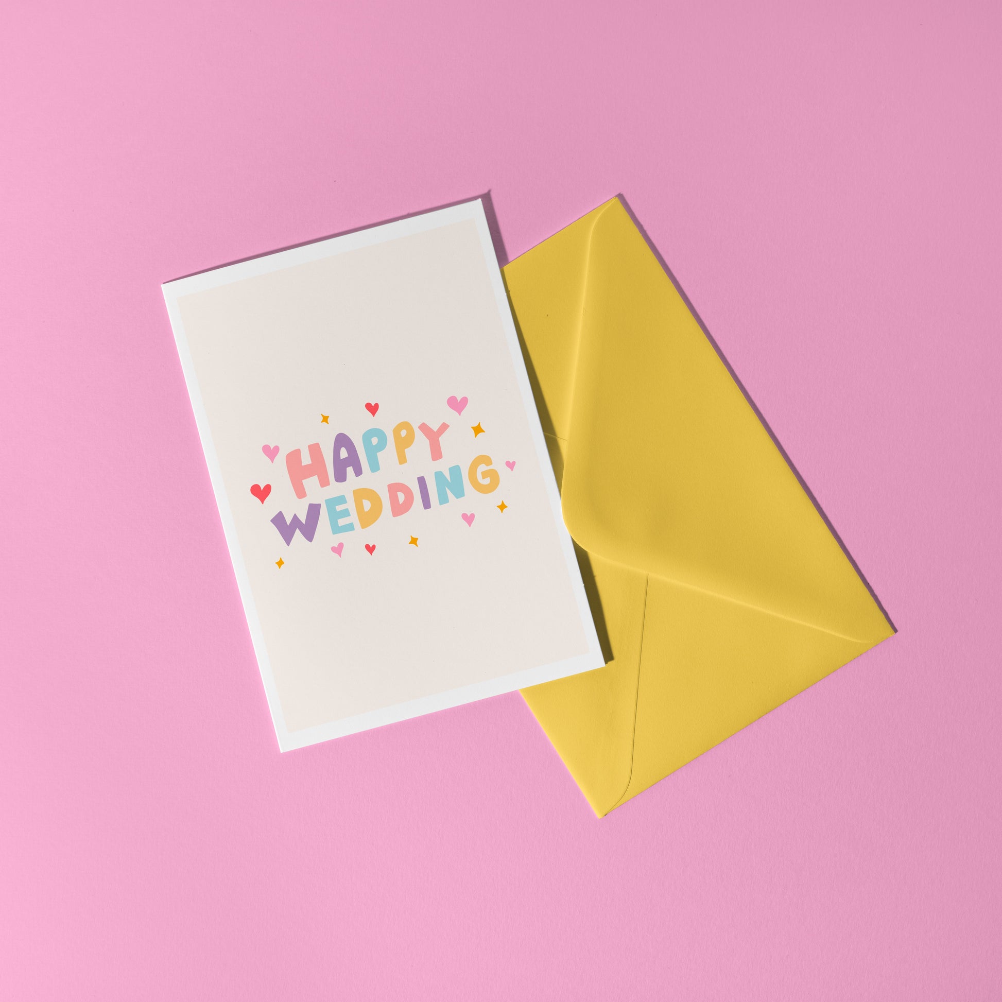 A minimalistic card with colourful hand lettering that reads 'Happy Wedding' with little heart and star doodles around it.