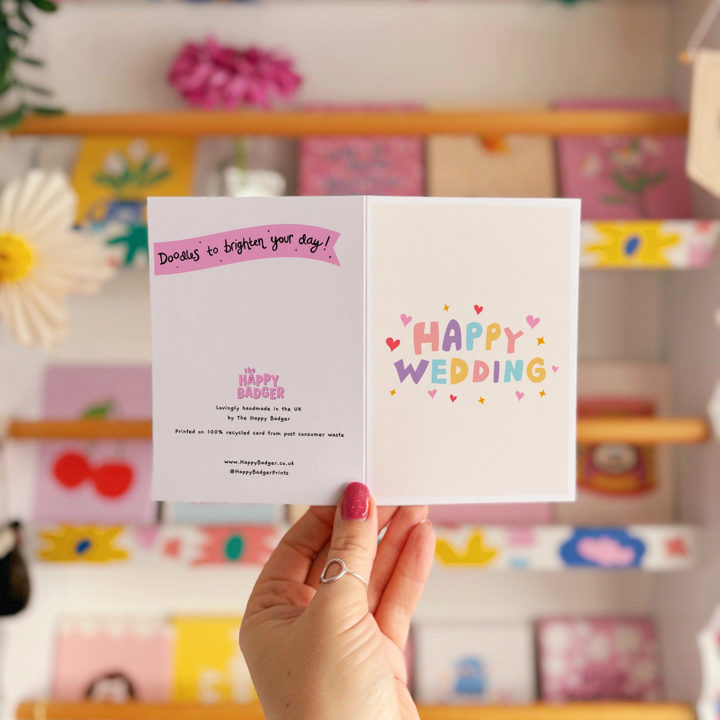 A minimalistic card with colourful hand lettering that reads 'Happy Wedding' with little heart and star doodles around it.