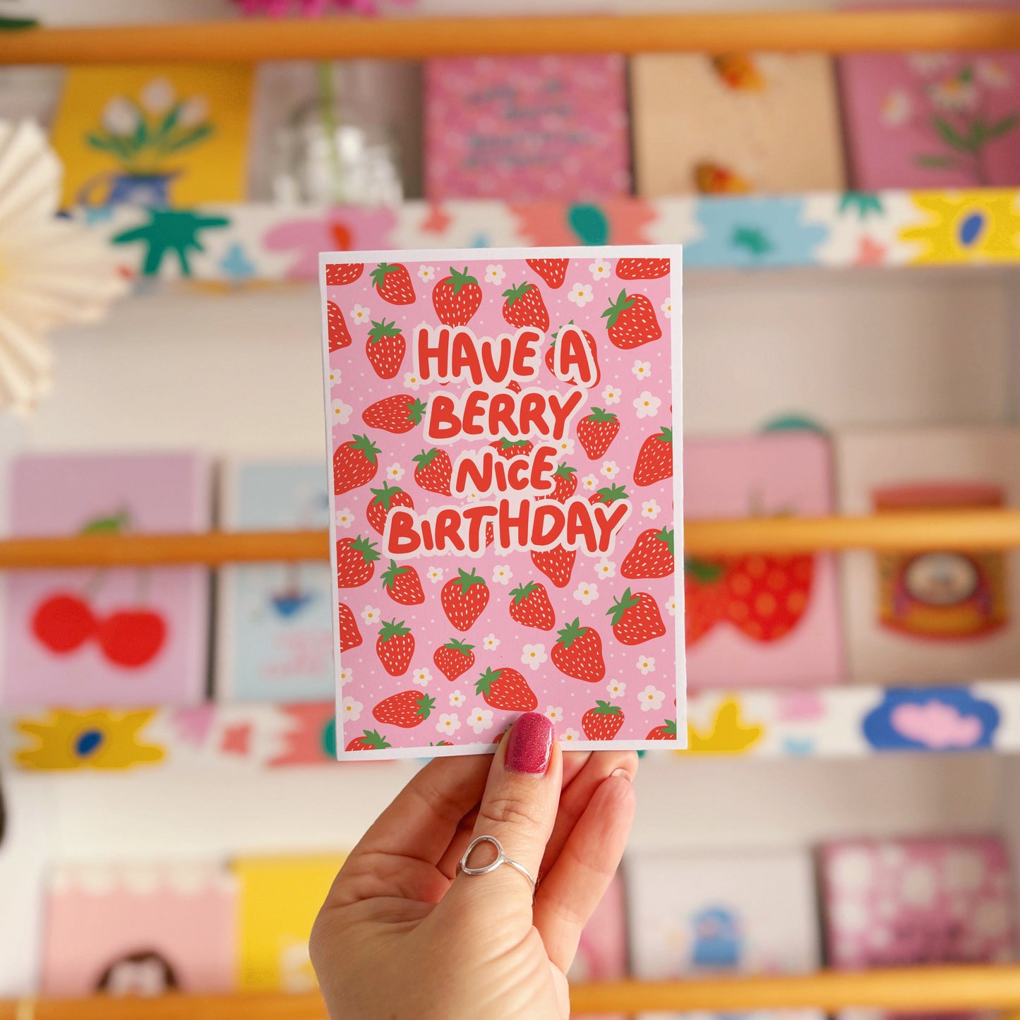A card with a strawberry pattern, and text that reads 'have a berry nice birthday' in red.