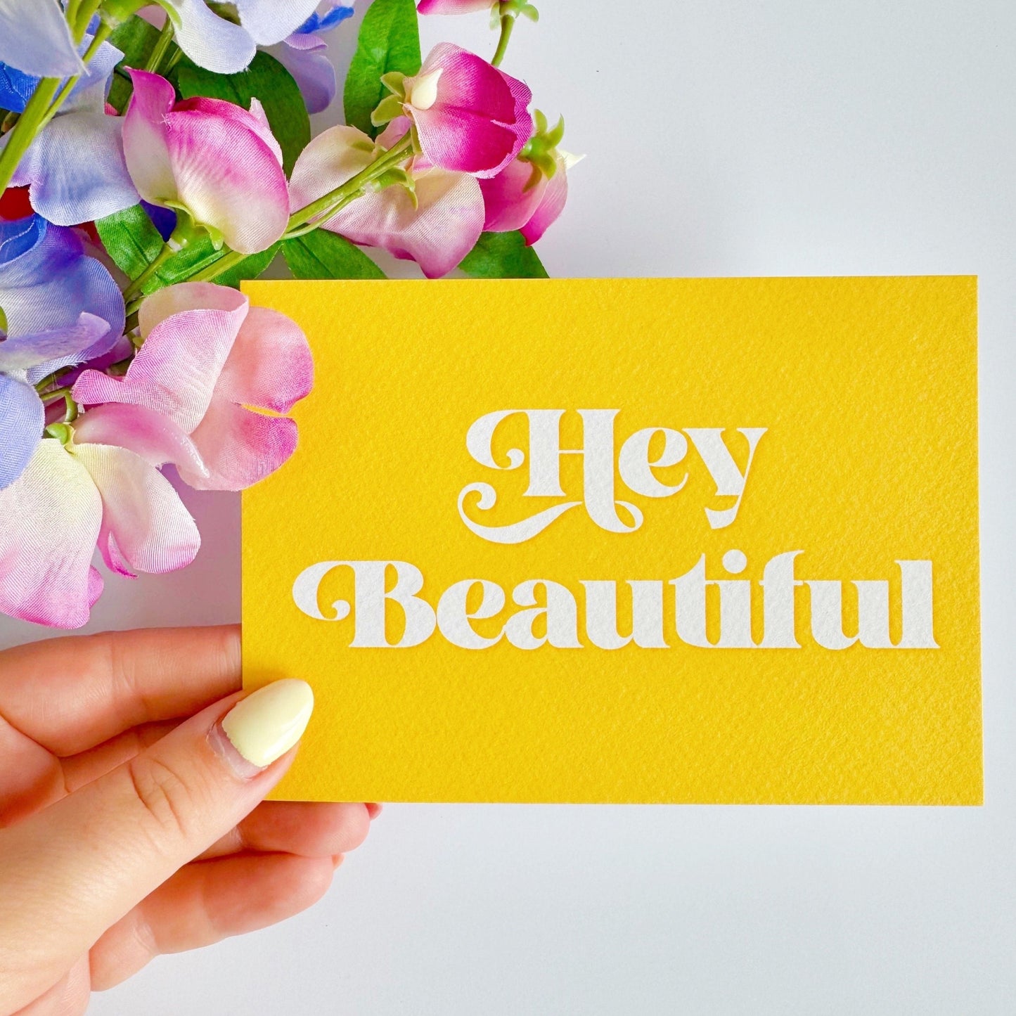 A textured postcard, with the words hello beautiful, on the front, on a yellow background.