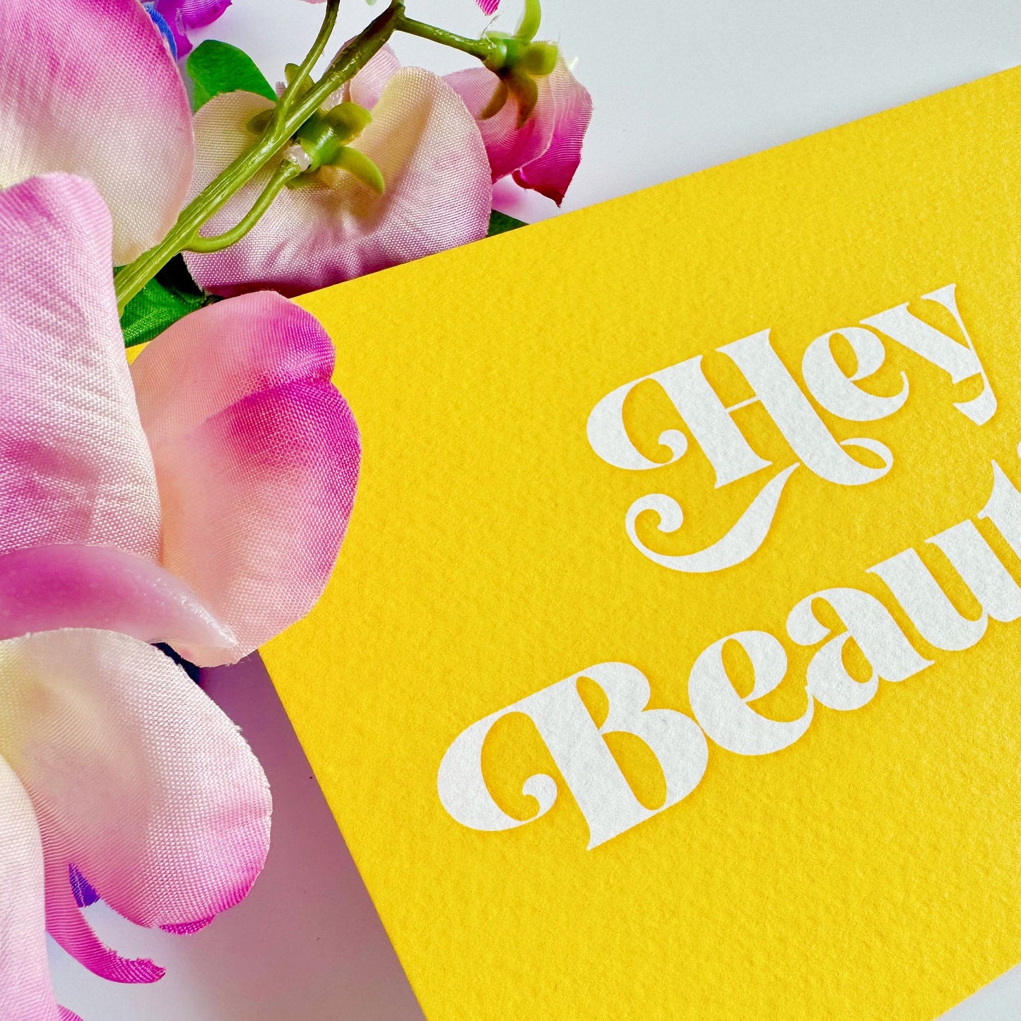 A textured postcard, with the words hello beautiful, on the front, on a yellow background.