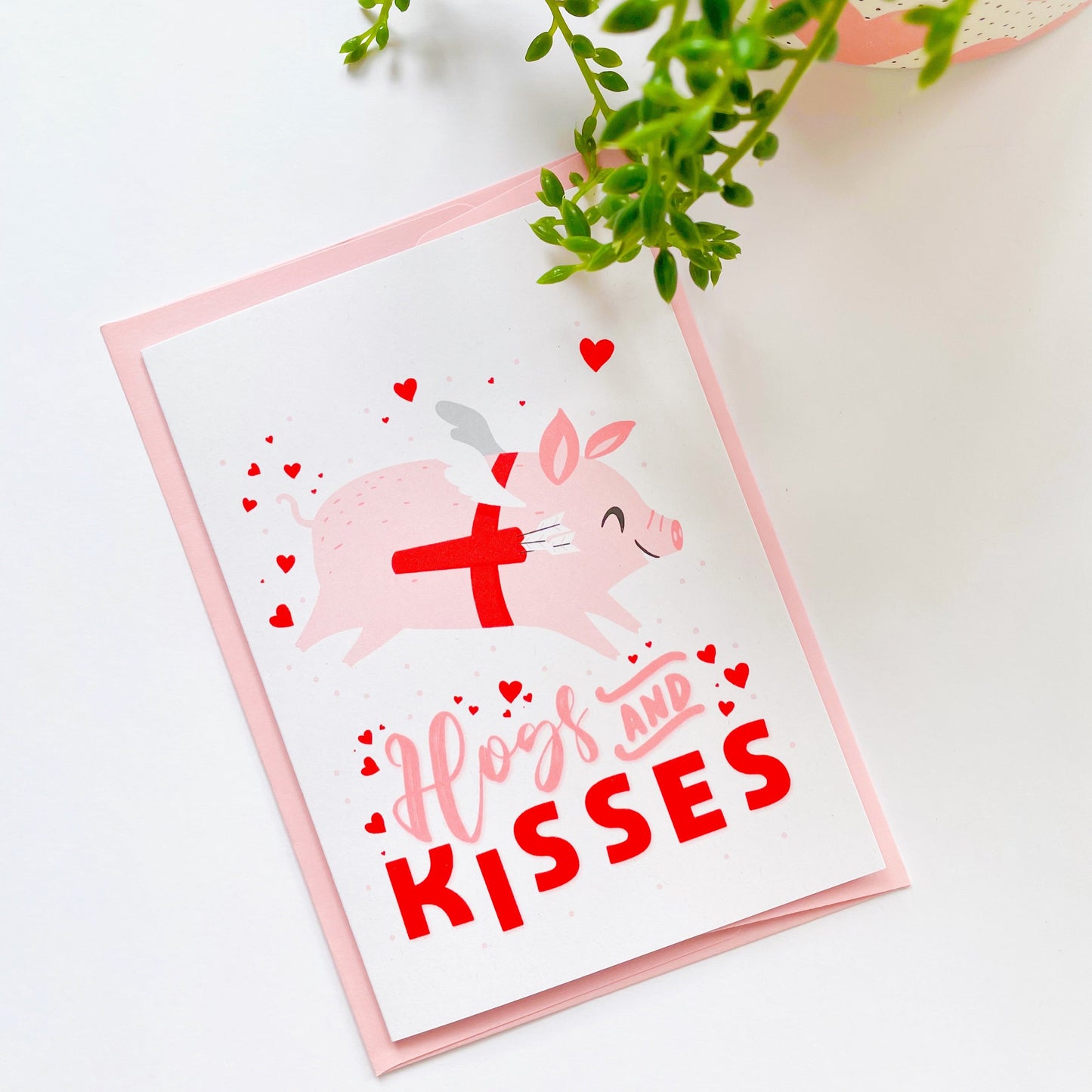 A love themed card, with a flying pig dressed as cupid and the words 'Hogs and kisses' underneath.