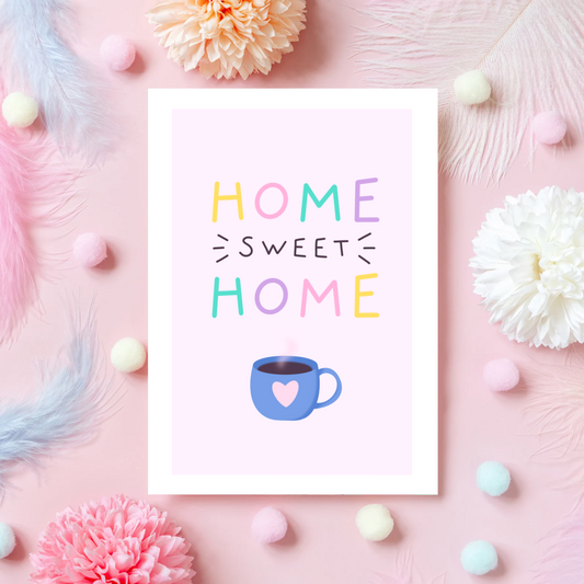 a pink card with text reading 'home sweet home' and a blue mug underneath with a heart on it.