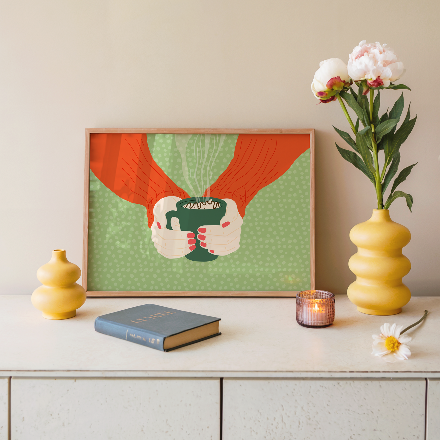 A green spotty print with an illustration of two hands holding a green mug with hot chocolate in.