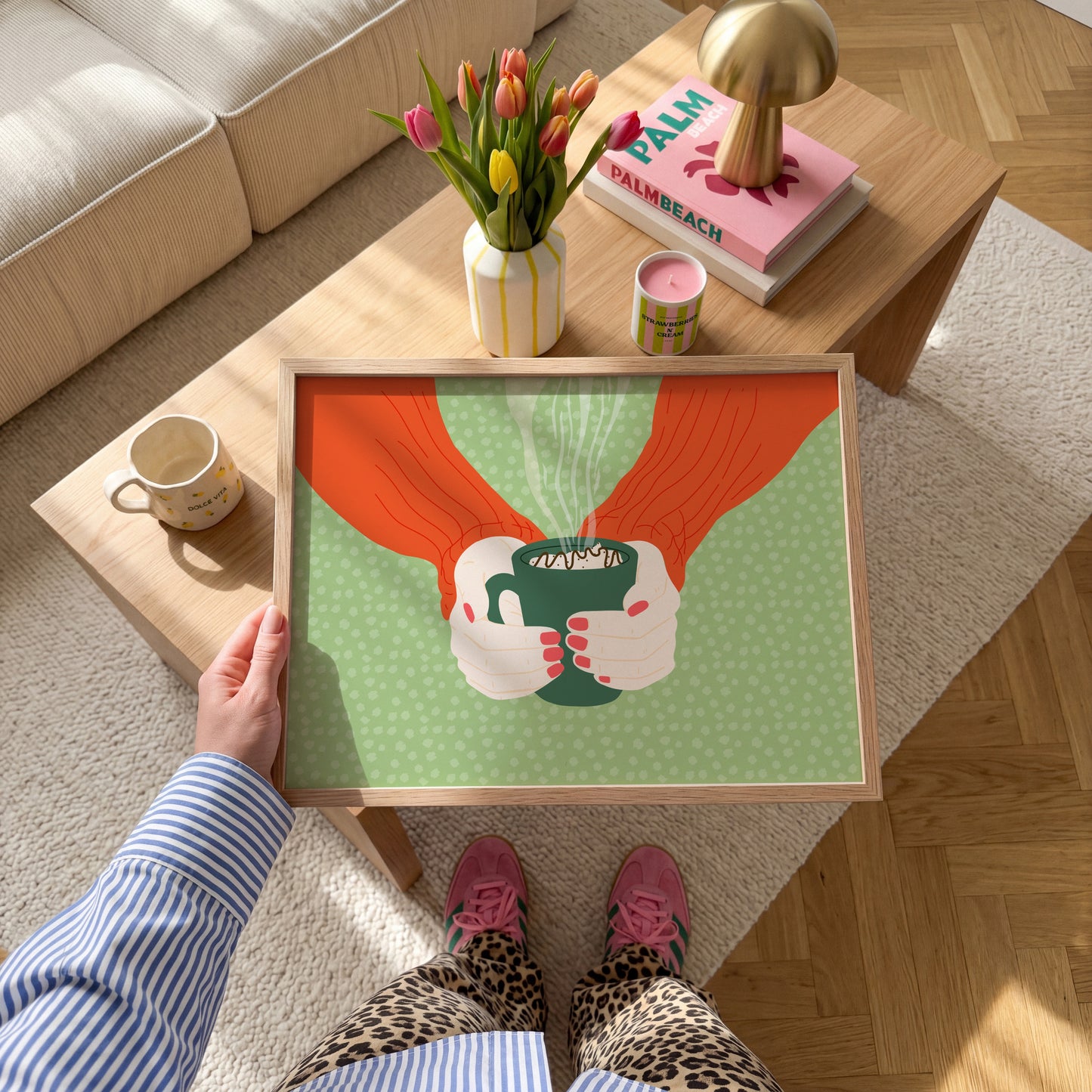 A green spotty print with an illustration of two hands holding a green mug with hot chocolate in.