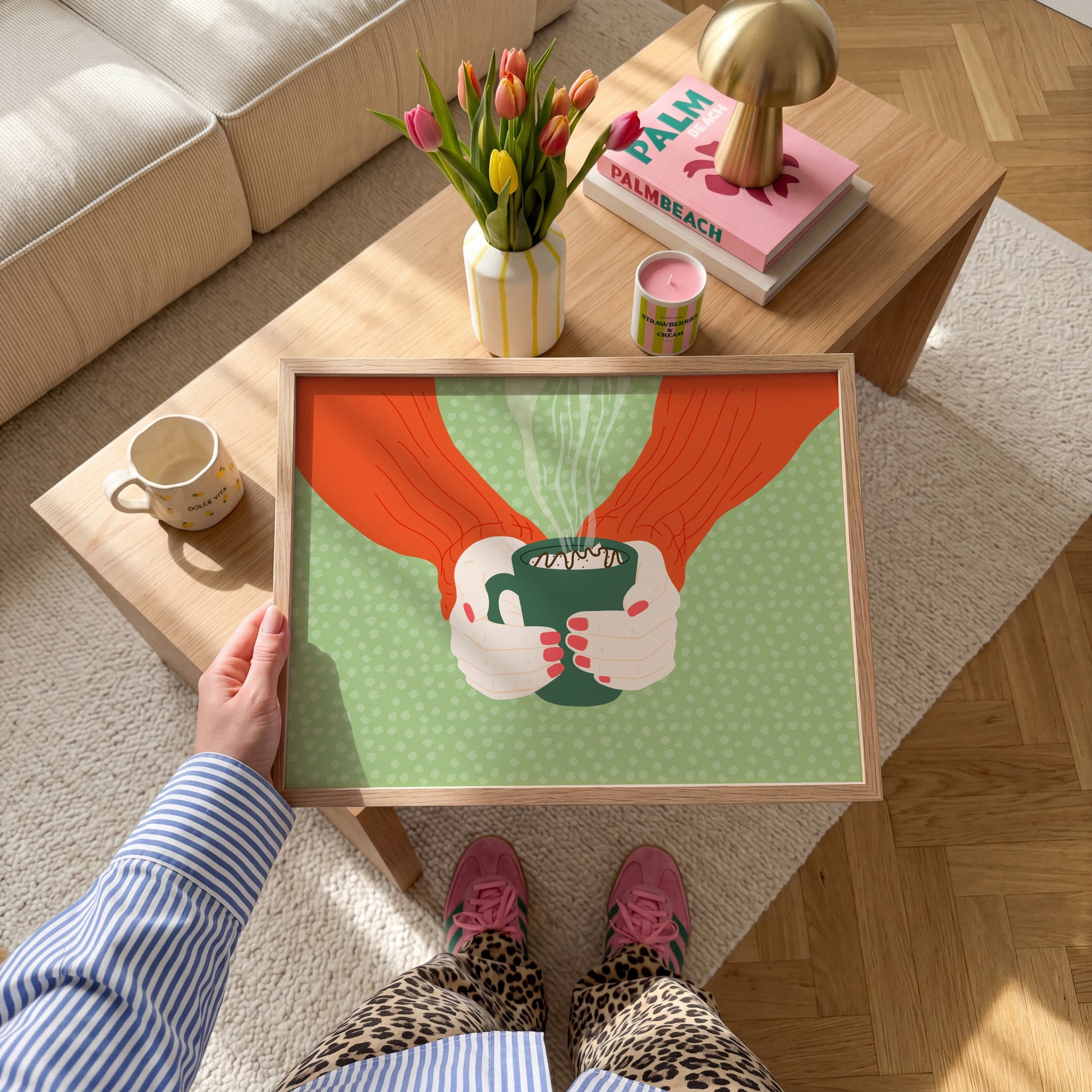 A green spotty print with an illustration of two hands holding a green mug with hot chocolate in.