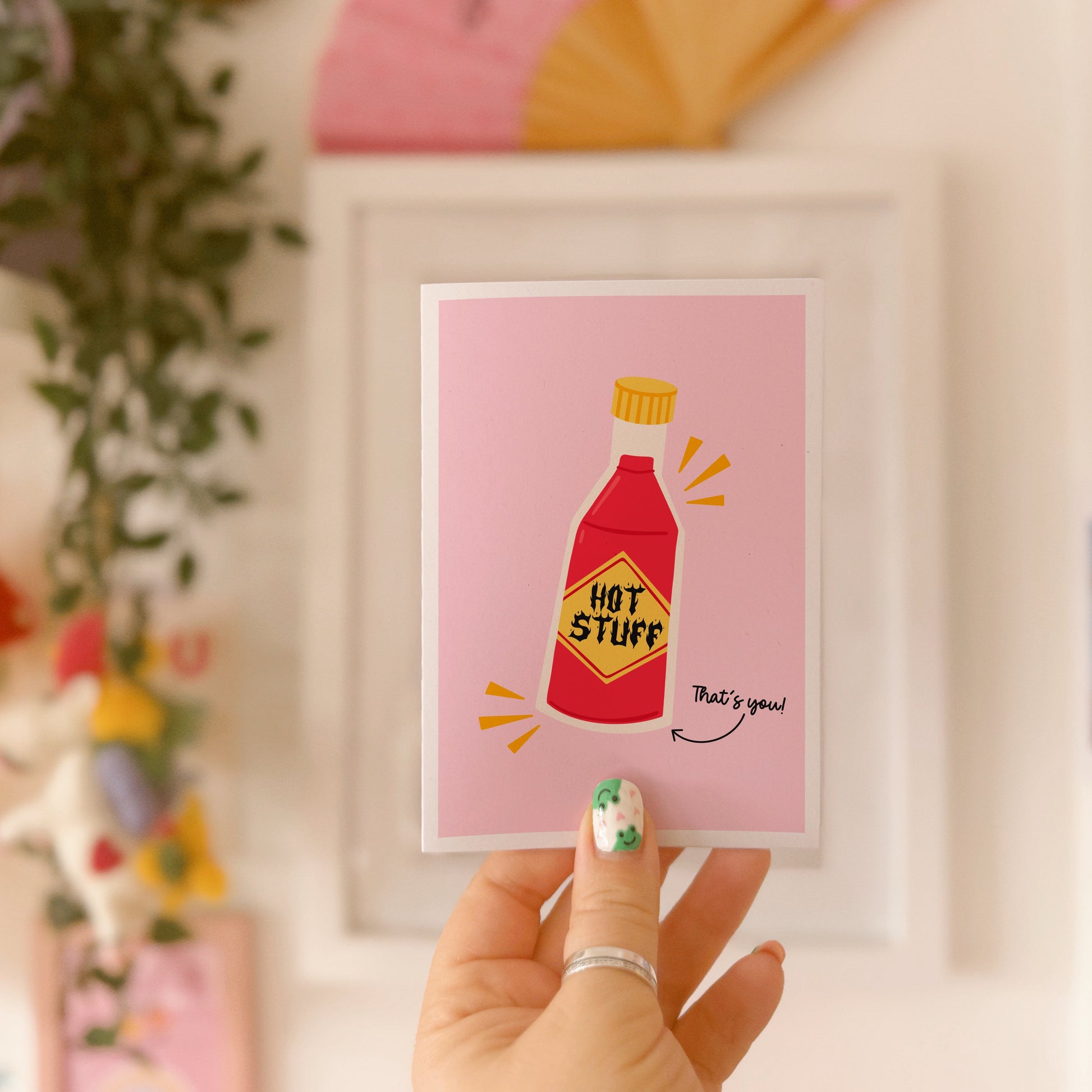 A pink love themed card with an illustration of a bottle of hot sauce on the front. The label on the hot sauce reads 'hot stuff' - with a hand written note next to it saying 'that's you!'.