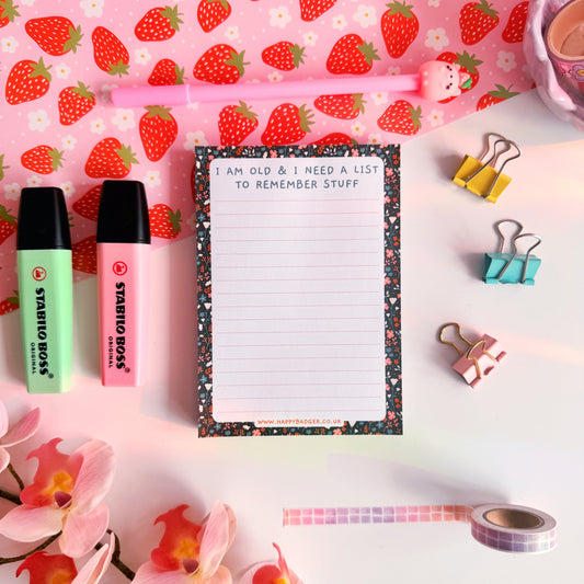 A lined notepad with a black floral pattern on the edges and a quote at the top that reads 'I am old and I need a list to remember stuff'.
