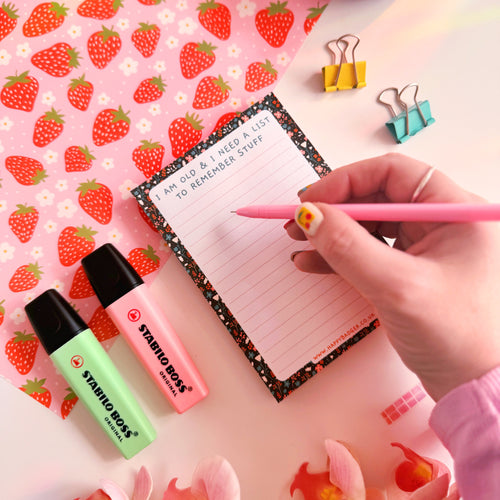 A lined notepad with a black floral pattern on the edges and a quote at the top that reads 'I am old and I need a list to remember stuff'.