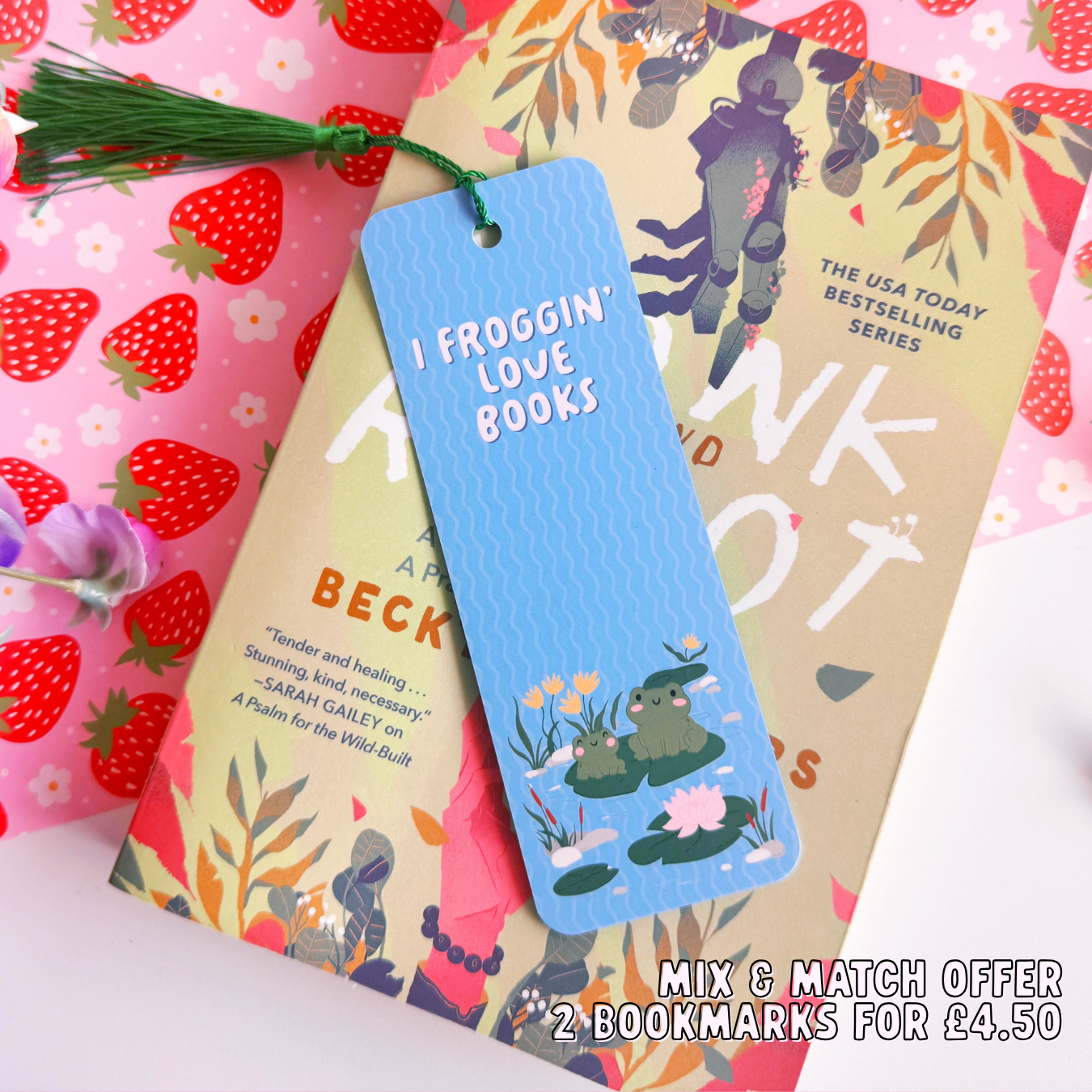 A blue bookmark with a cute frog illustration to both the front and back of the bookmark, on the front of the bookmark it says 'I Froggin' Love Books' and on the back of the bookmark is the brand logo.