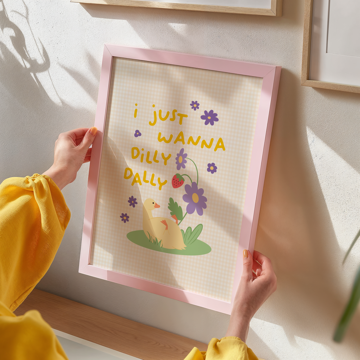 An illustrated print featuring an illustration of a duck sitting beneath a flower stem with the text 'I just wanna dilly dally' surrounded by purple florals and a yellow gingham background.