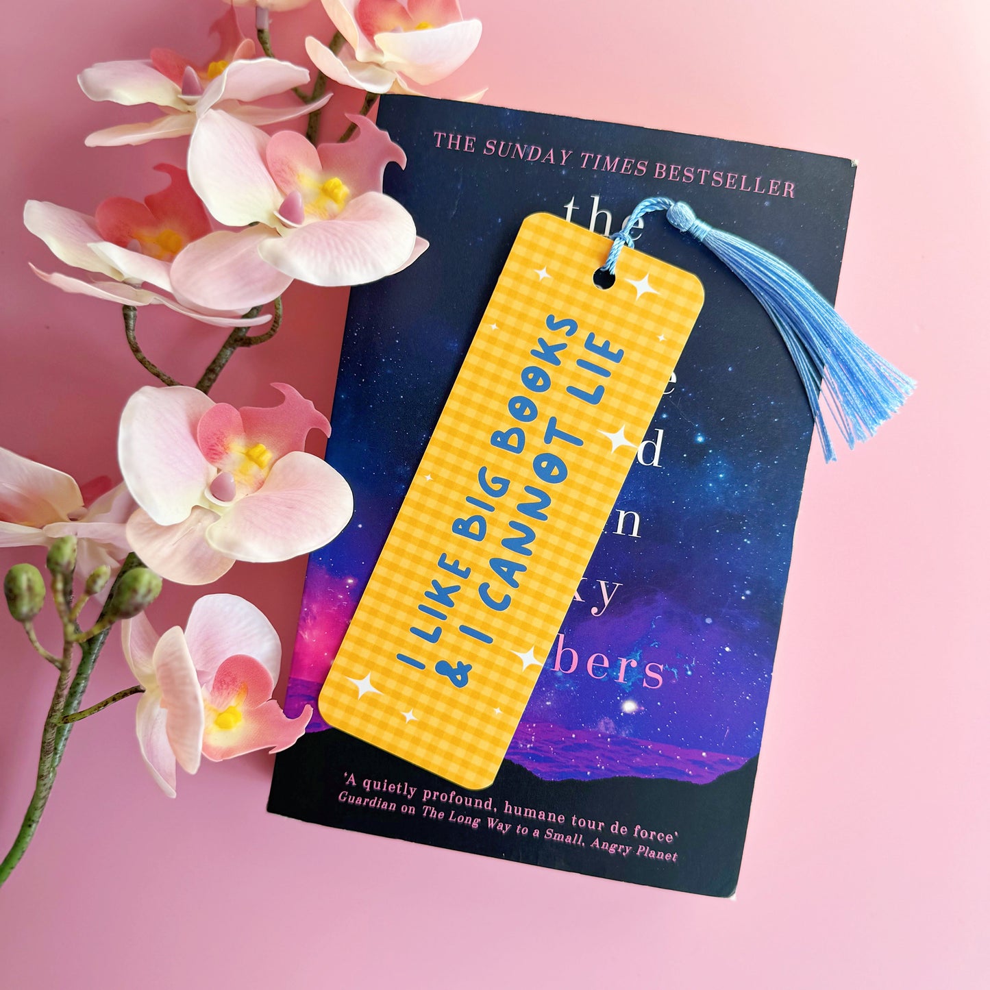 A yellow gingham bookmark, with a blue tassel, and blue text that reads 'I like big books and I cannot lie'.