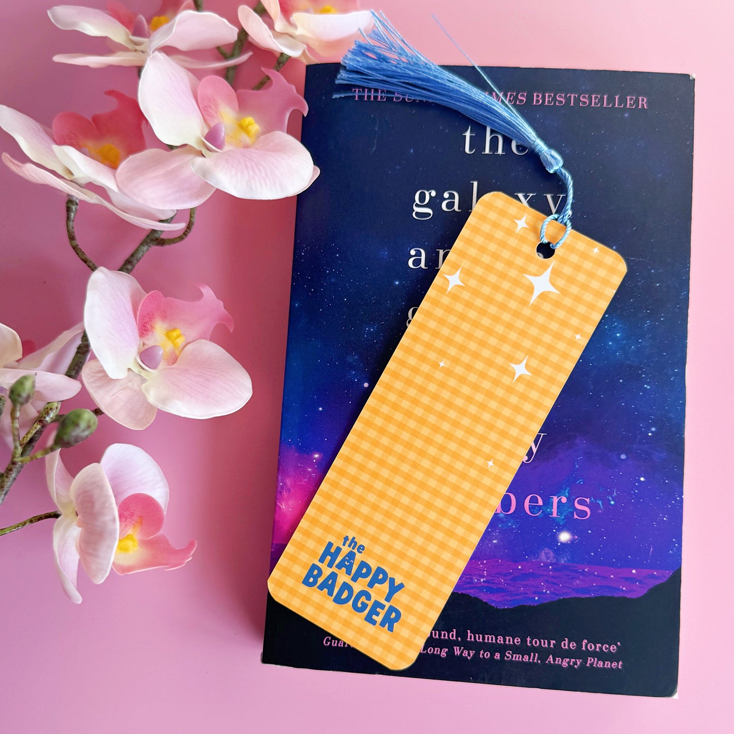 A yellow gingham bookmark, with a blue tassel, and blue text that reads 'I like big books and I cannot lie'.