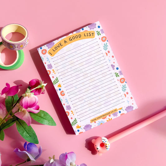 Notebook with floral design on a pink background with flowers and tape.