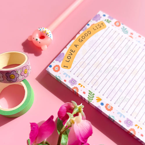 Floral-themed notepad with decorative tape and flowers on a pink background