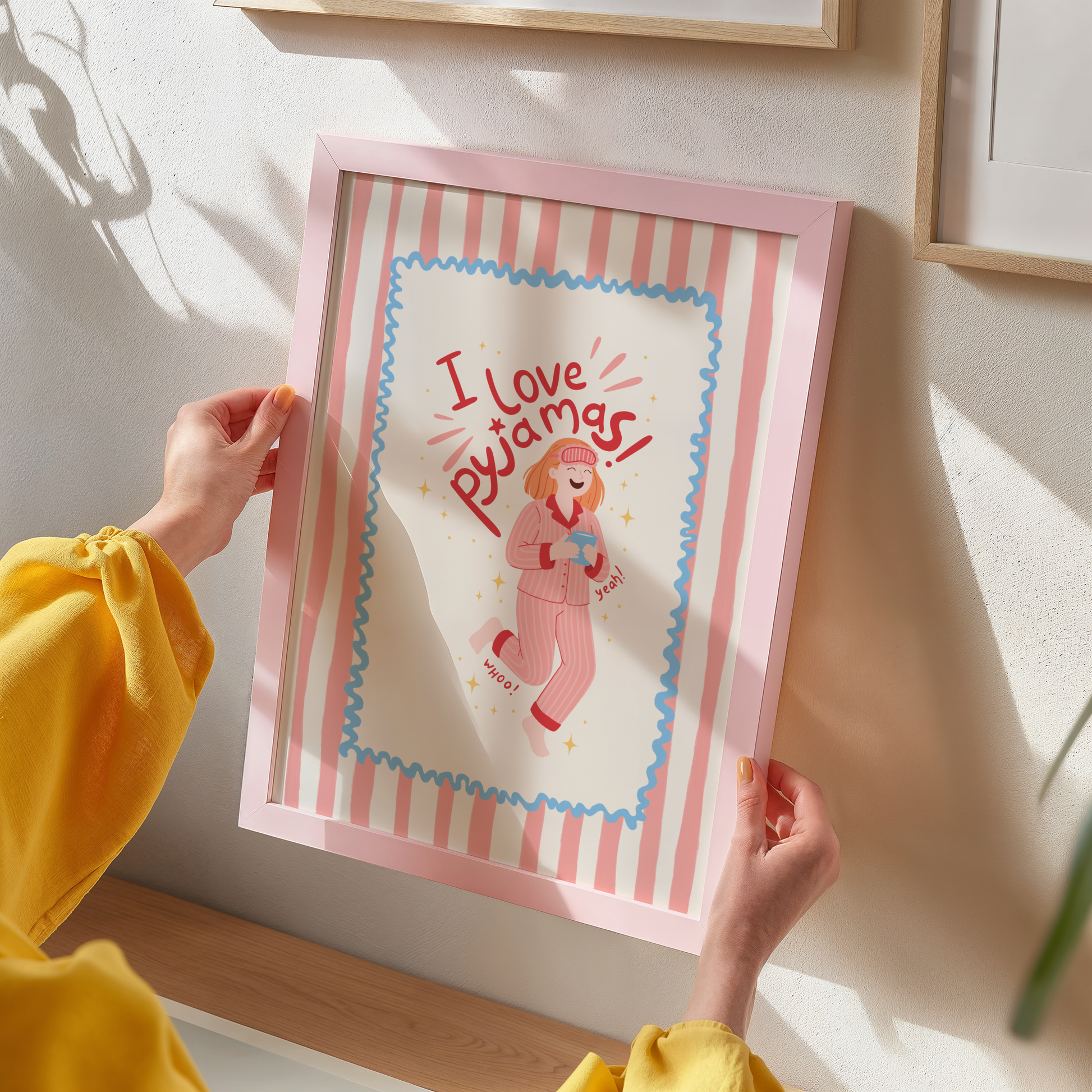 Person holding a framed illustration with 'I love pajamas' text and a person in pajamas.