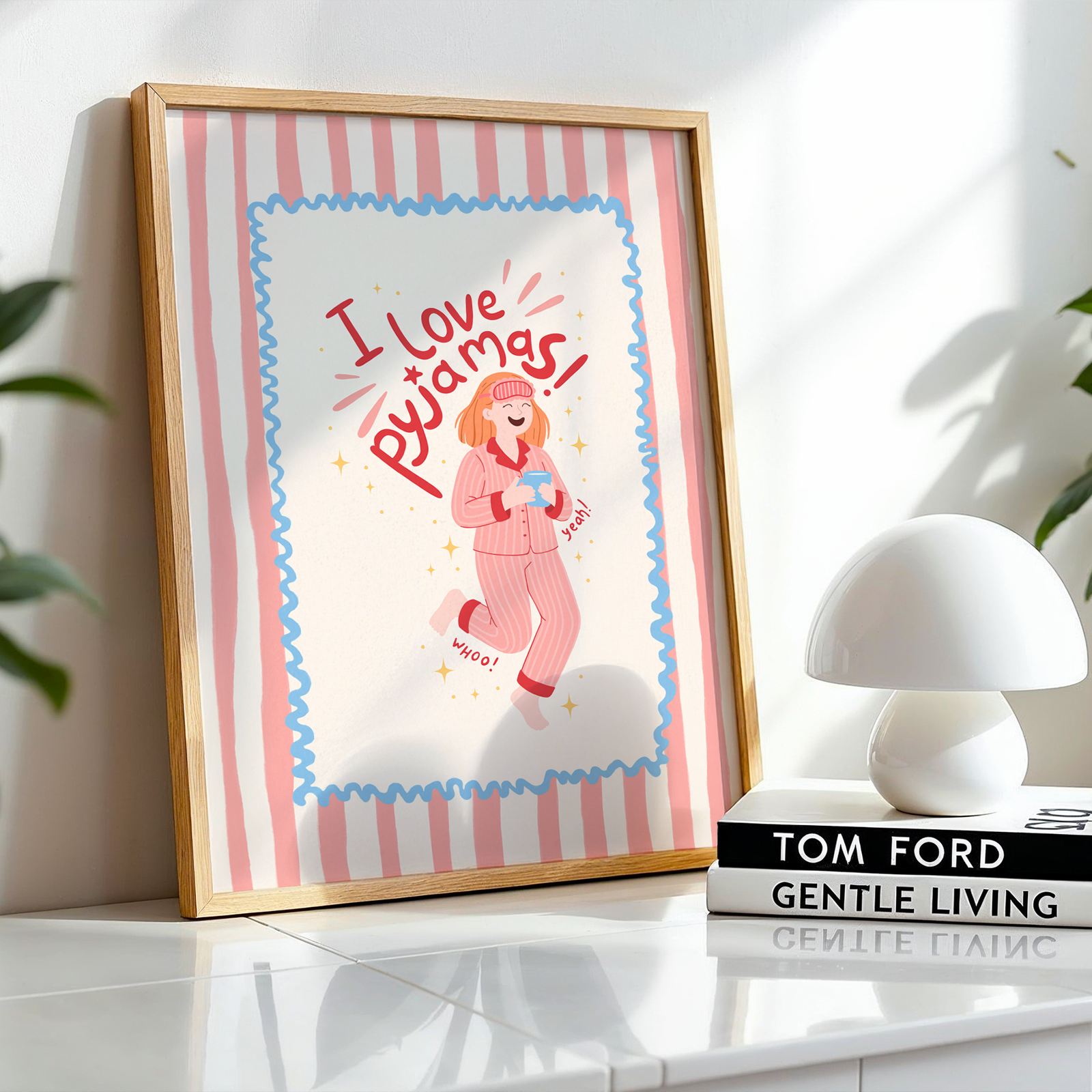 Framed artwork with a cartoon character and text on a shelf with books and plants.