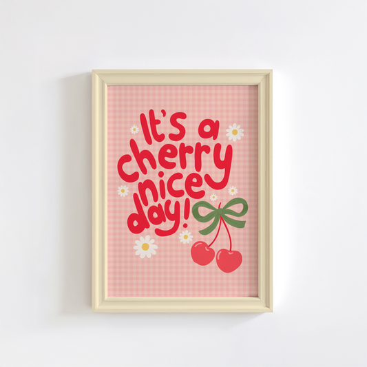 A gingham print, with hand lettered text that reads 'it's a cherry nice day!' in red. The text is surrounded by little daisy illustrations and a large pair of cherries tied together with a green bow.