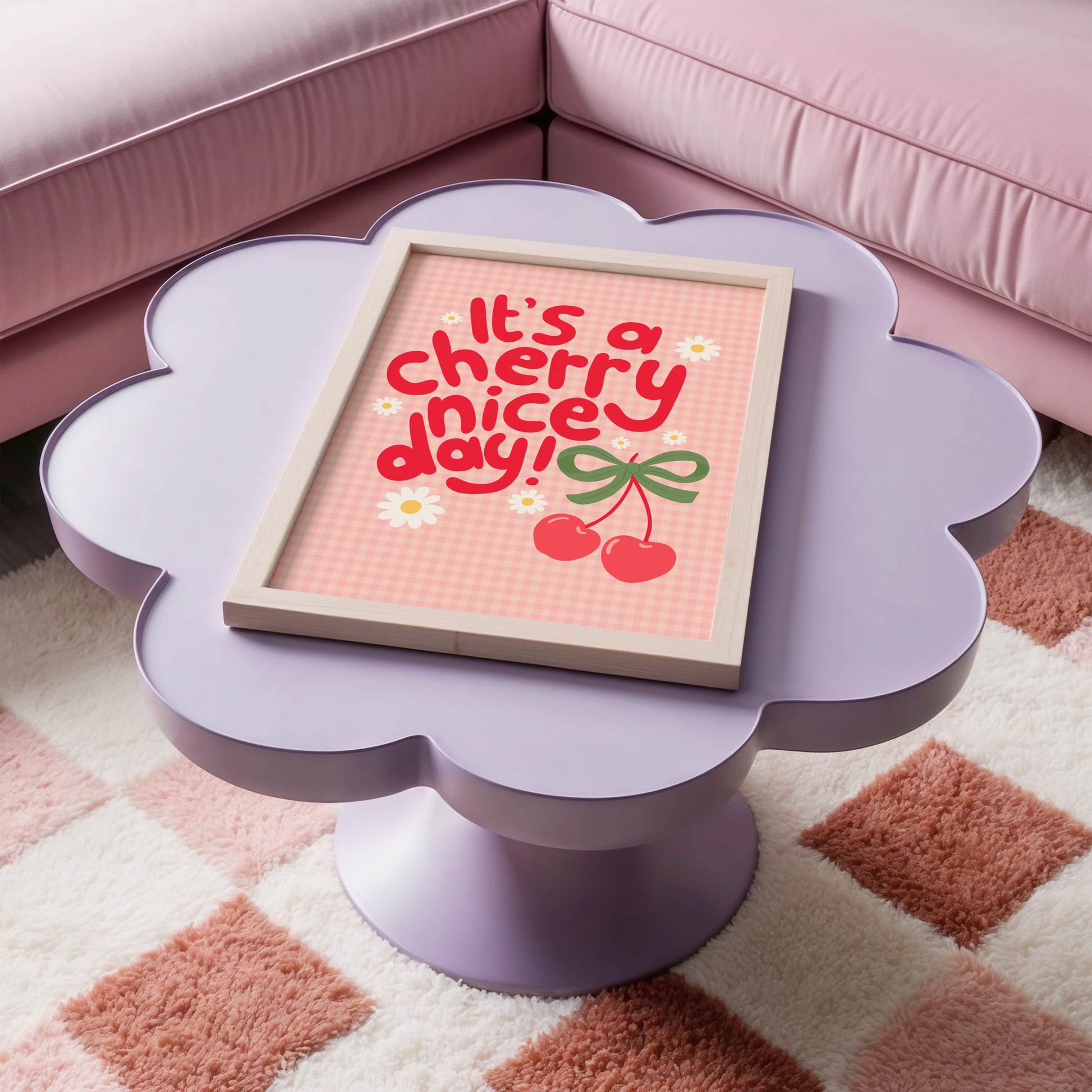 A gingham print, with hand lettered text that reads 'it's a cherry nice day!' in red. The text is surrounded by little daisy illustrations and a large pair of cherries tied together with a green bow.