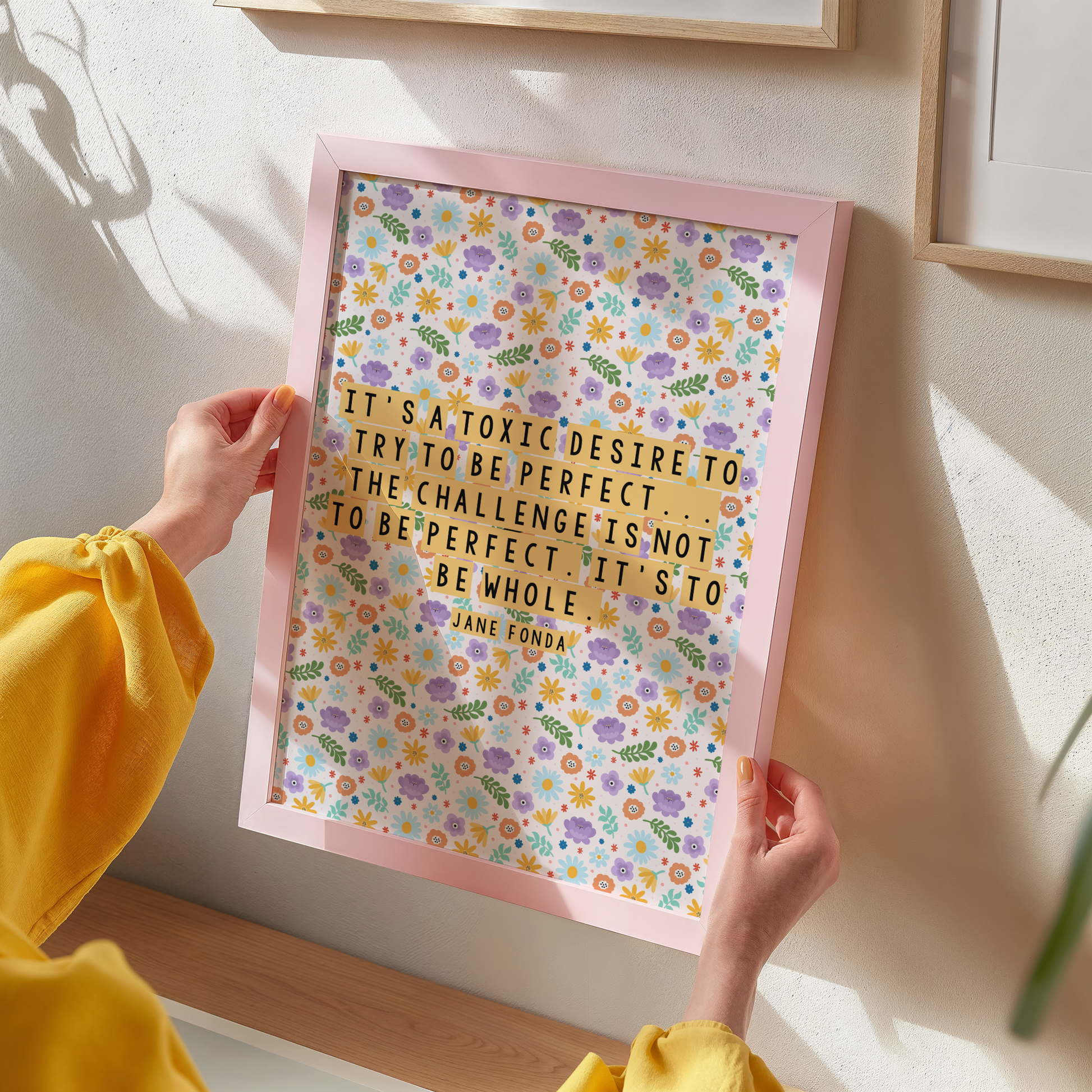 A framed print with a colourful floral pattern background featuring a quote by Jane Fonda.