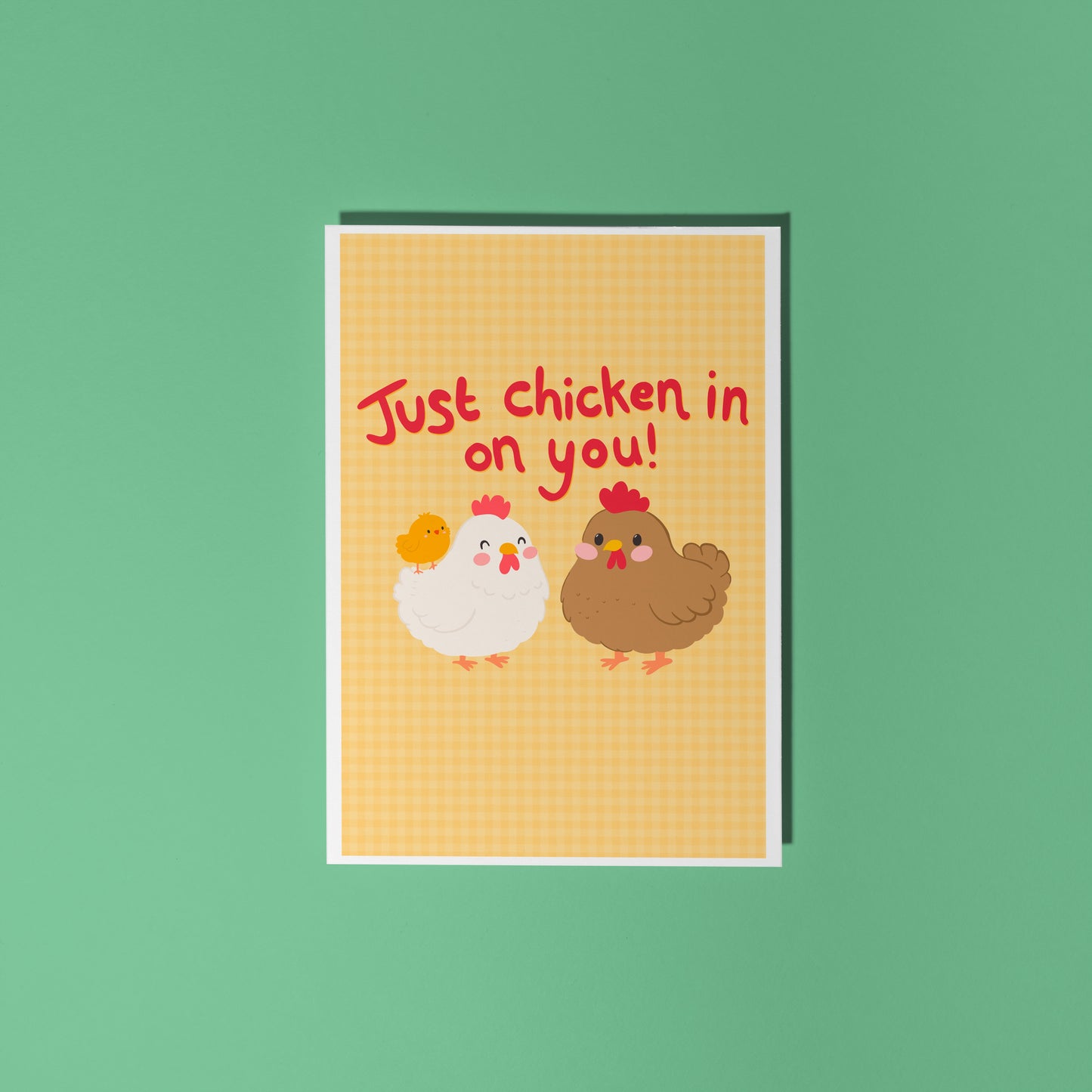 Card with chicken illustrations and red text that says 'Just chicken in on you!', with a yellow gingham background.