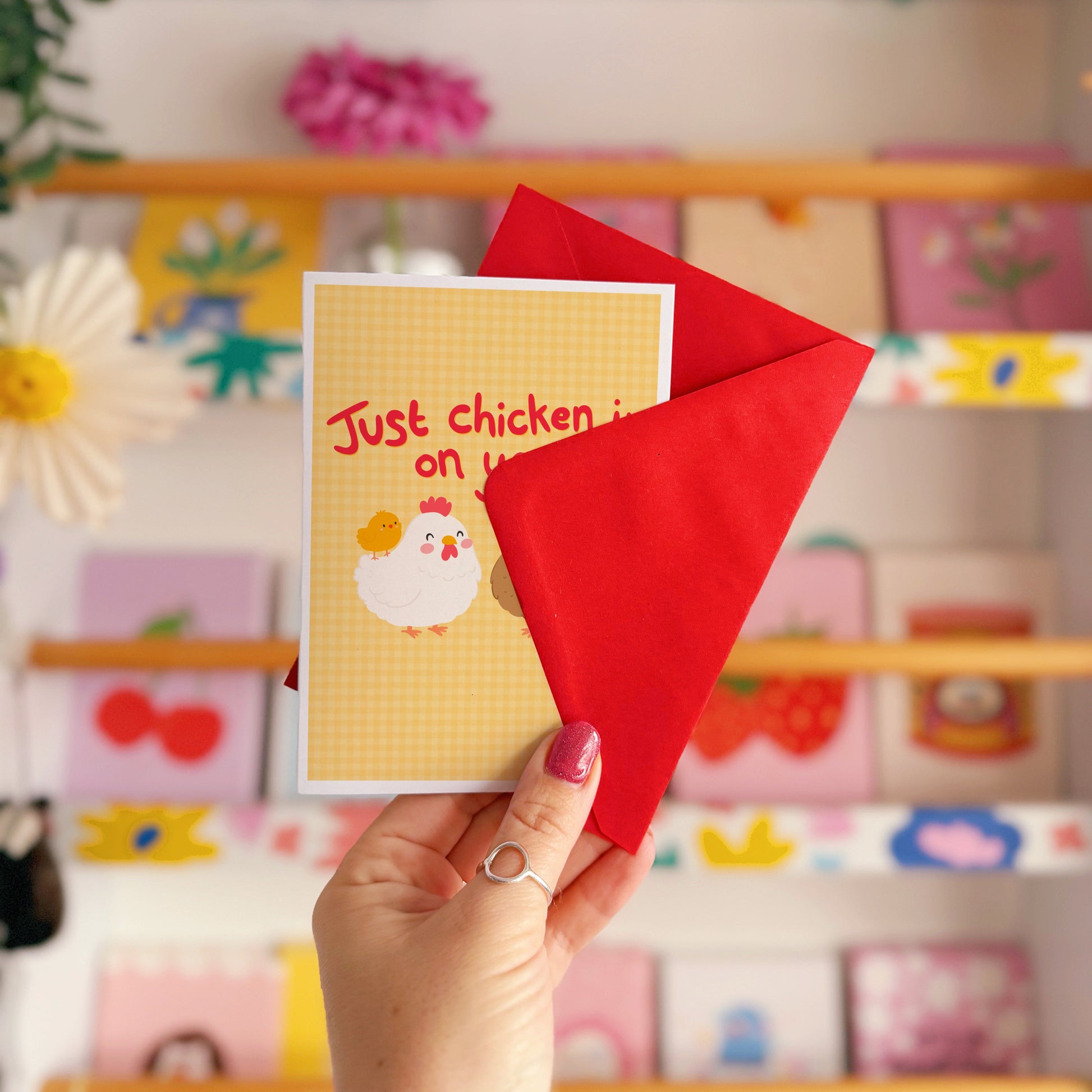 Card with chicken illustrations and red text that says 'Just chicken in on you!', with a yellow gingham background.