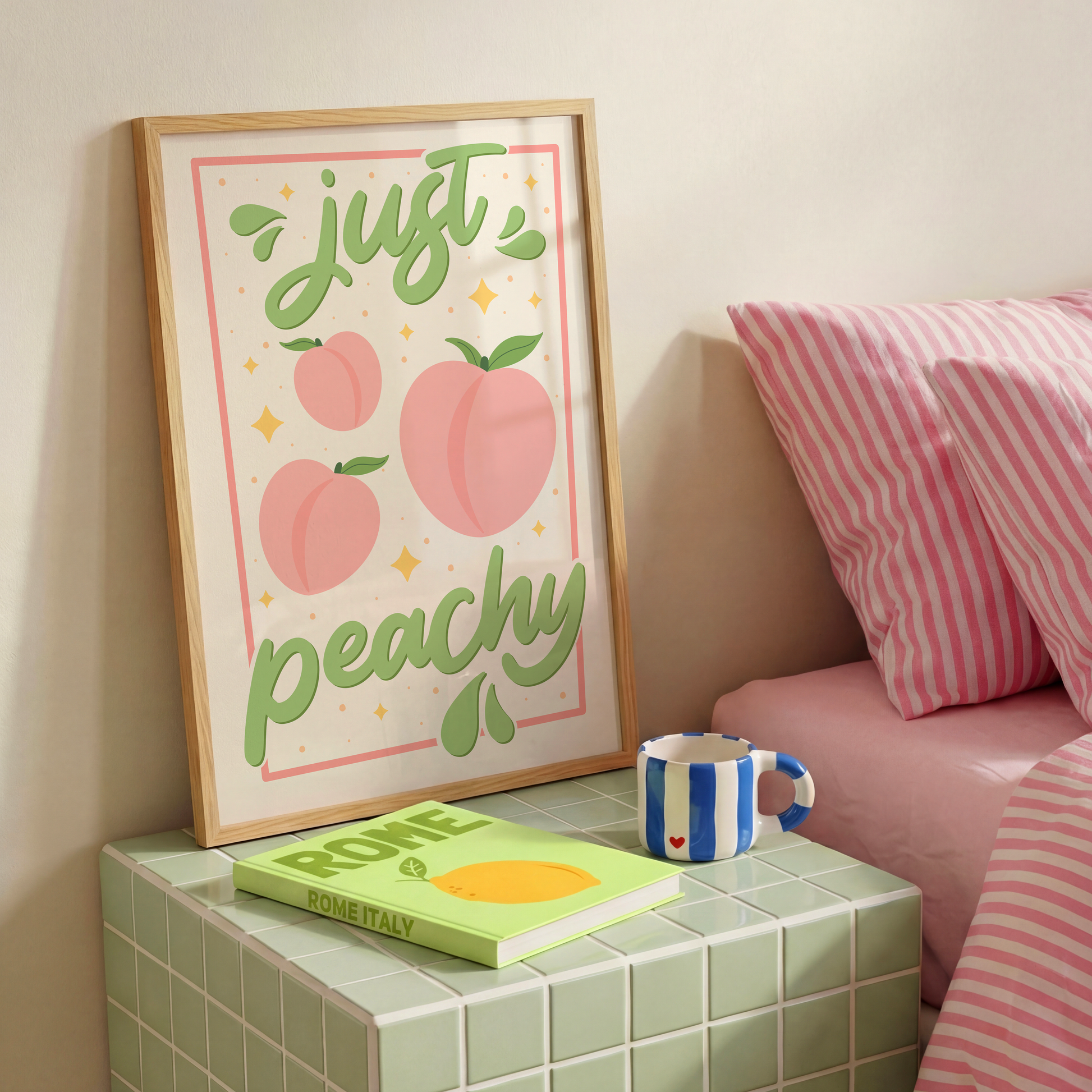 An art print with the text 'just peachy' hand-lettered in teal script, accompanied by illustrations of pink peaches and leaves, and a soft pink border.