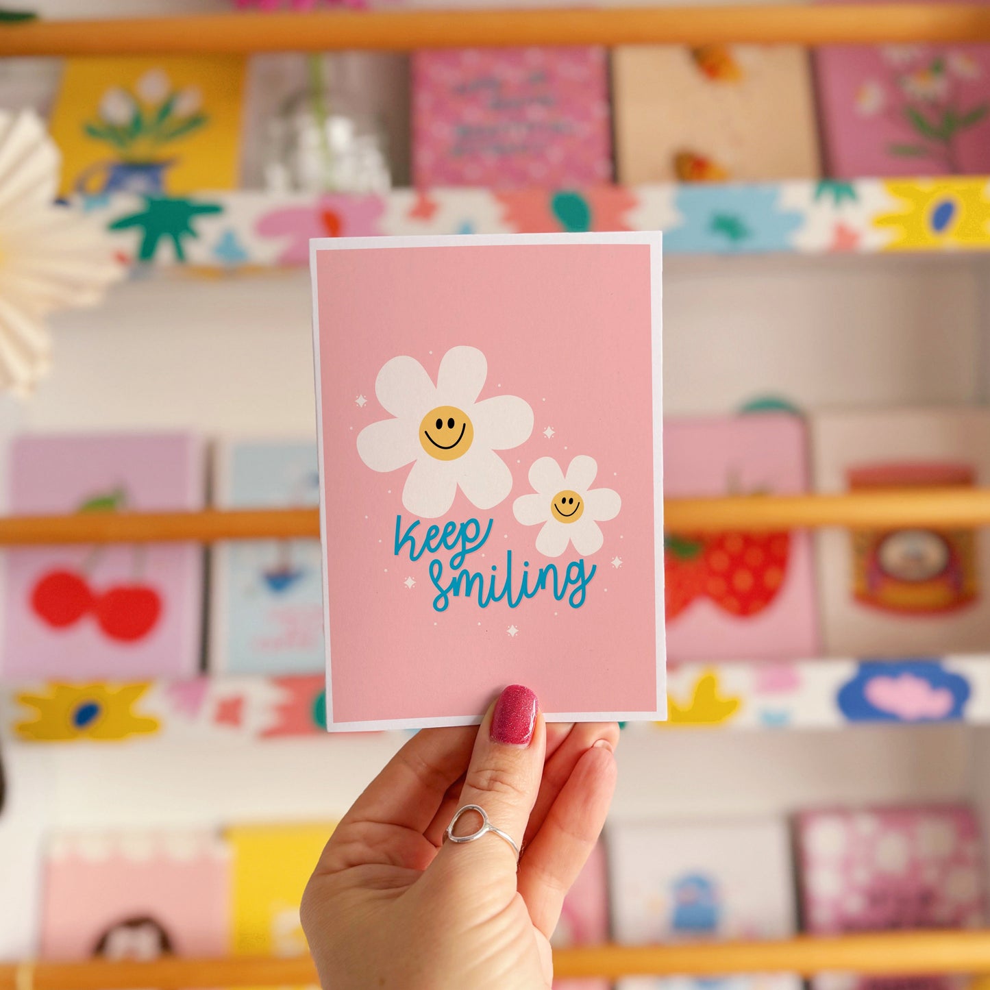 Card with smiley flowers and 'Keep smiling' text on a pink background