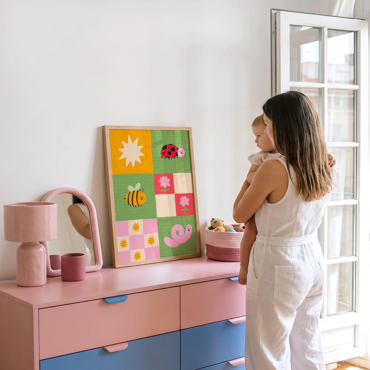 A framed children's art print. The illustration features colourful cartoon motifs including a ladybug, bee, worm, flowers, and suns on green, pink, yellow, and cream squares.