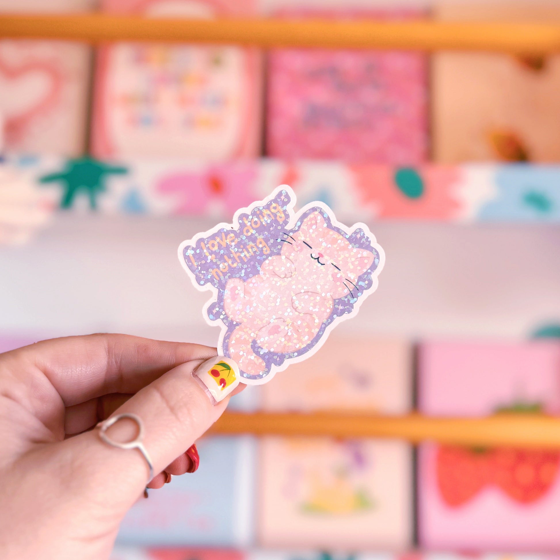 A holographic sticker featuring an illustration of a lazy cat and a quote that reads 'I love doing nothing'.