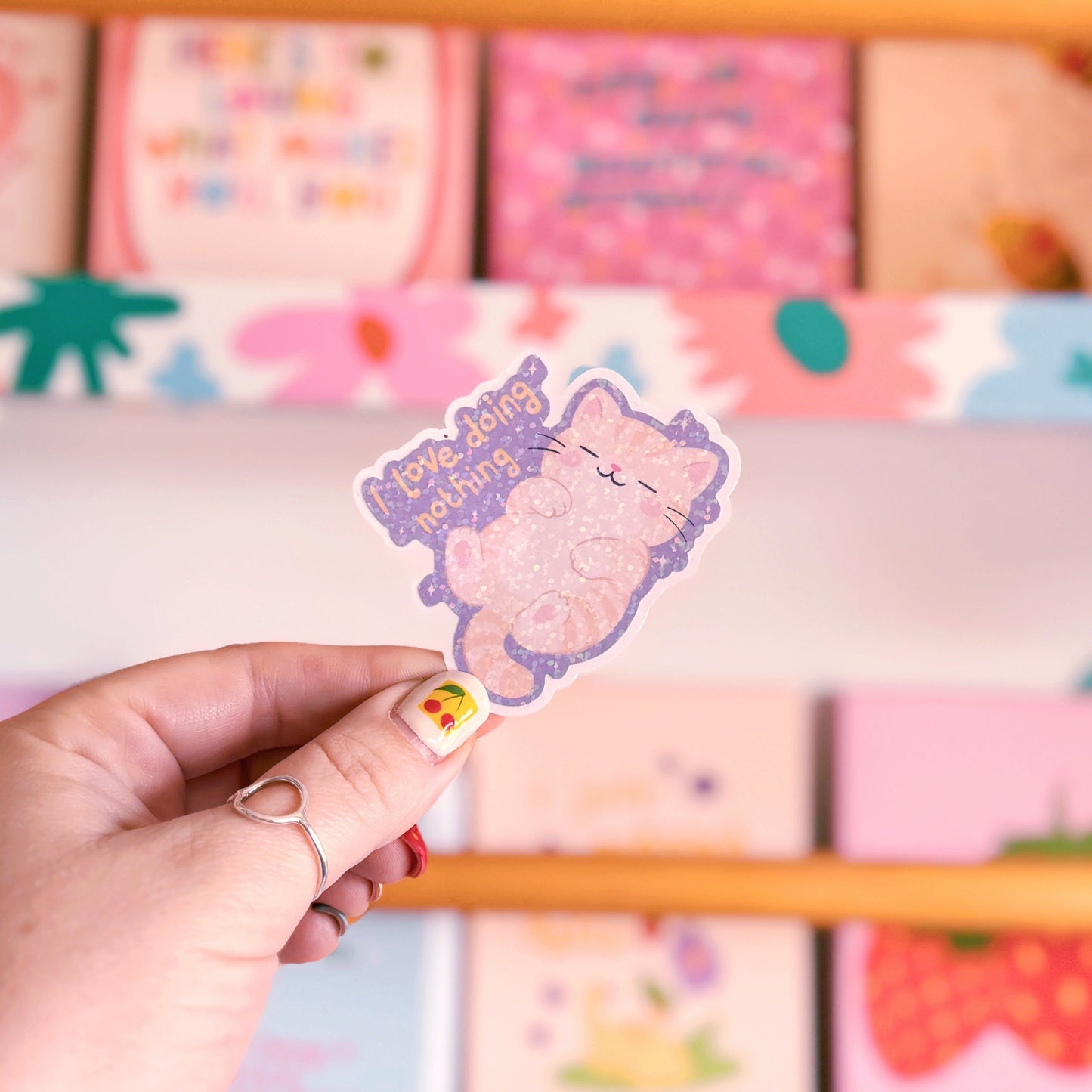 A holographic sticker featuring an illustration of a lazy cat and a quote that reads 'I love doing nothing'.